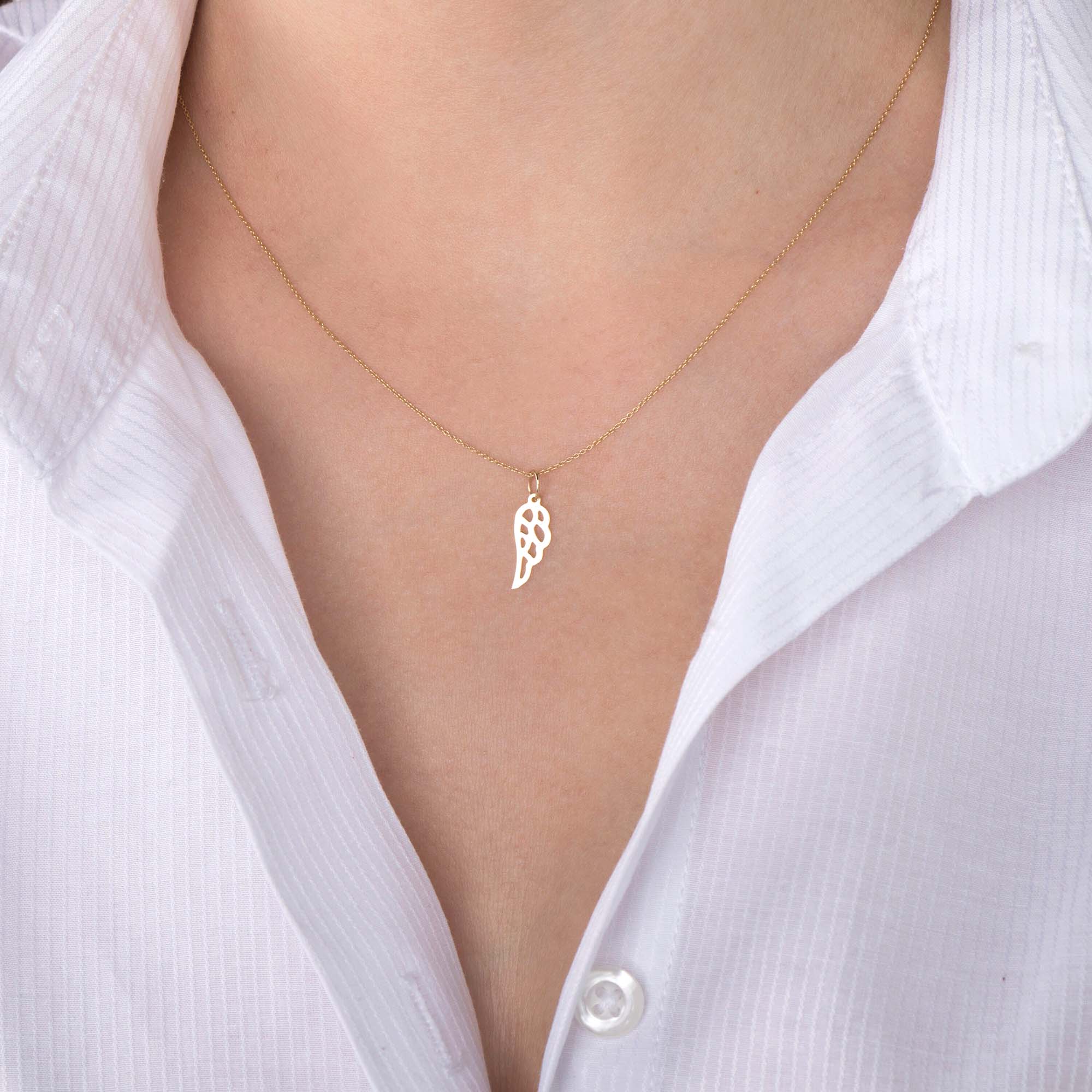 An image of a minimal angel wing pendant necklace worn by a model.