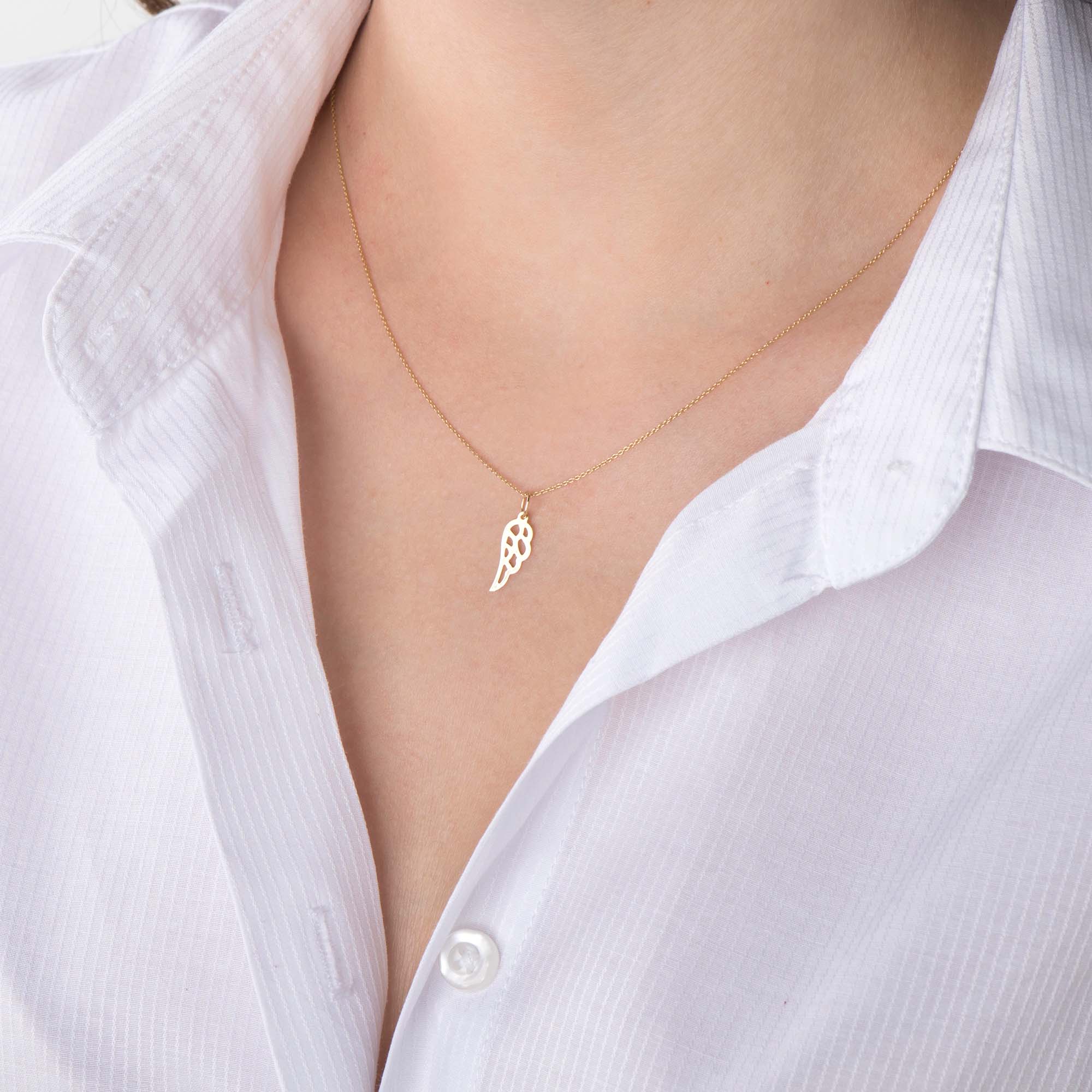 An image of a minimal angel wing pendant necklace worn by a model.