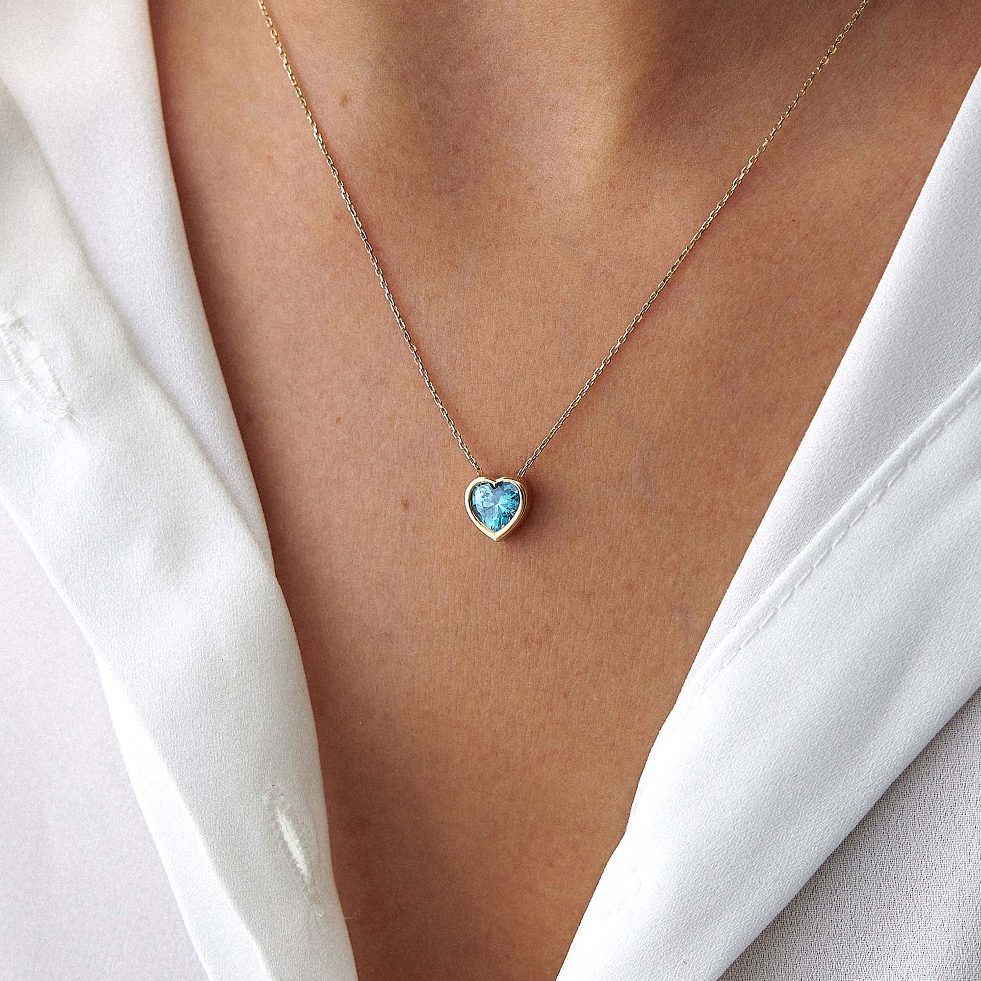 Heart-shaped blue gemstone necklace on a person wearing a white shirt