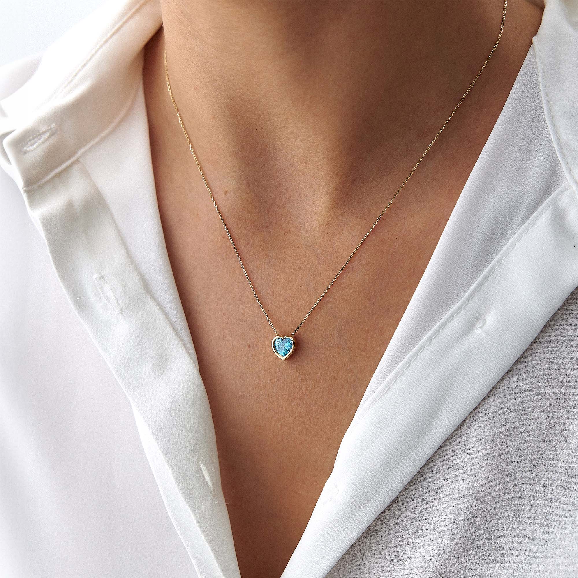 Heart-shaped blue gemstone necklace on a person wearing a white shirt