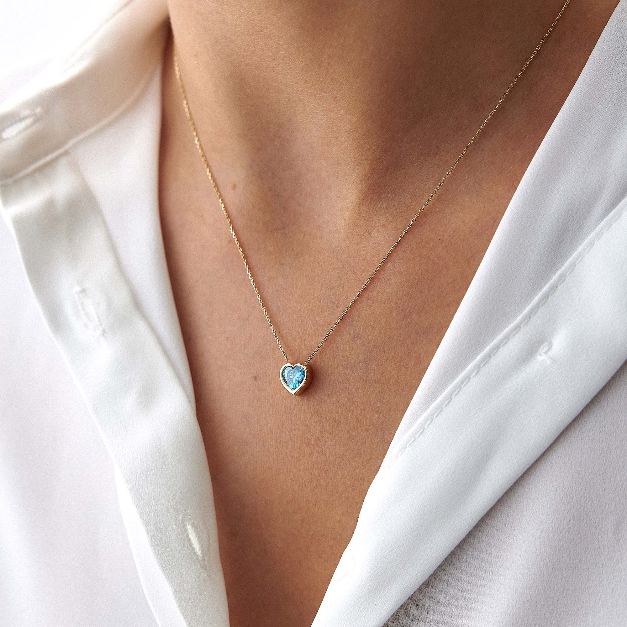 Heart-shaped blue gemstone necklace on a person wearing a white shirt