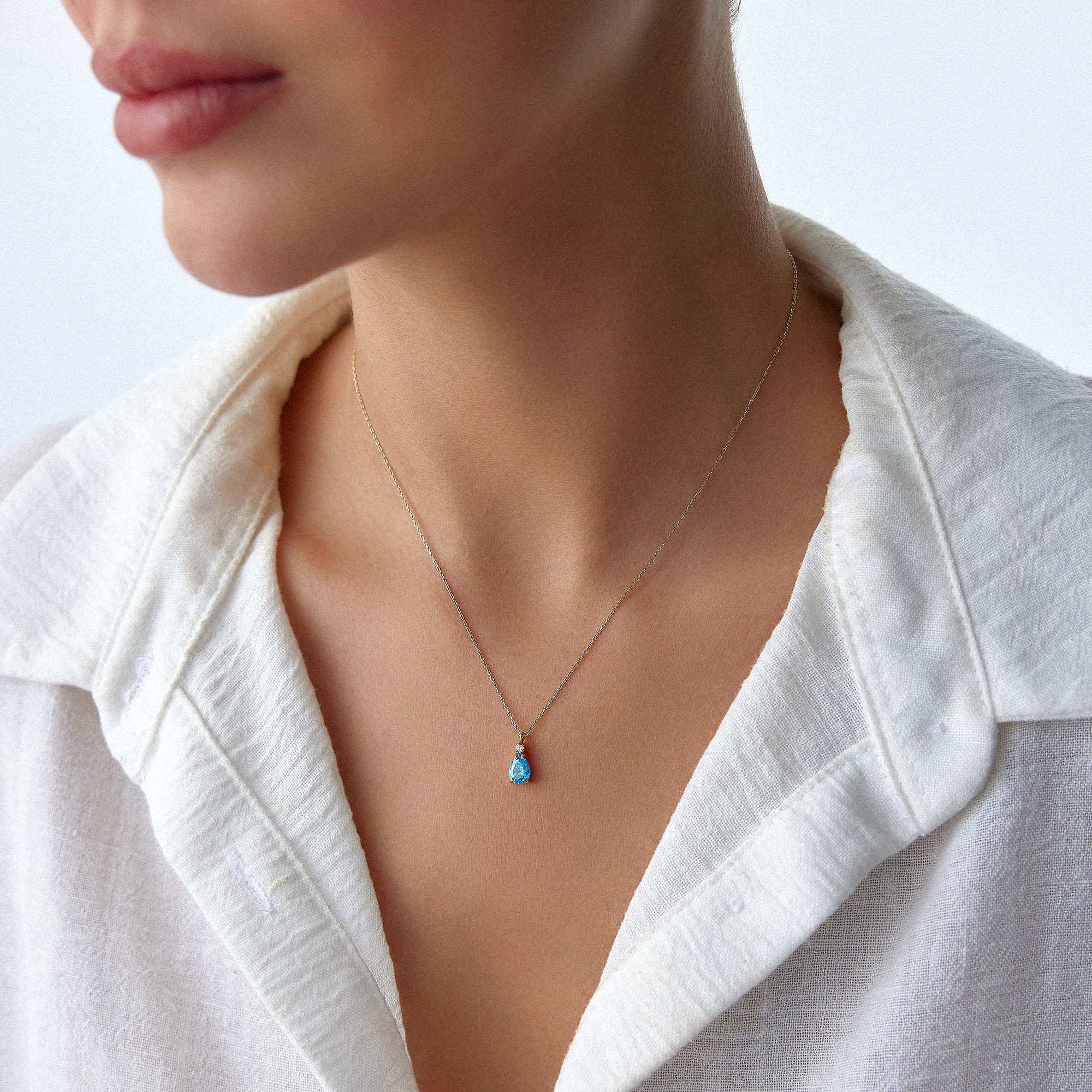 Necklace with a blue drop pendant worn by a person