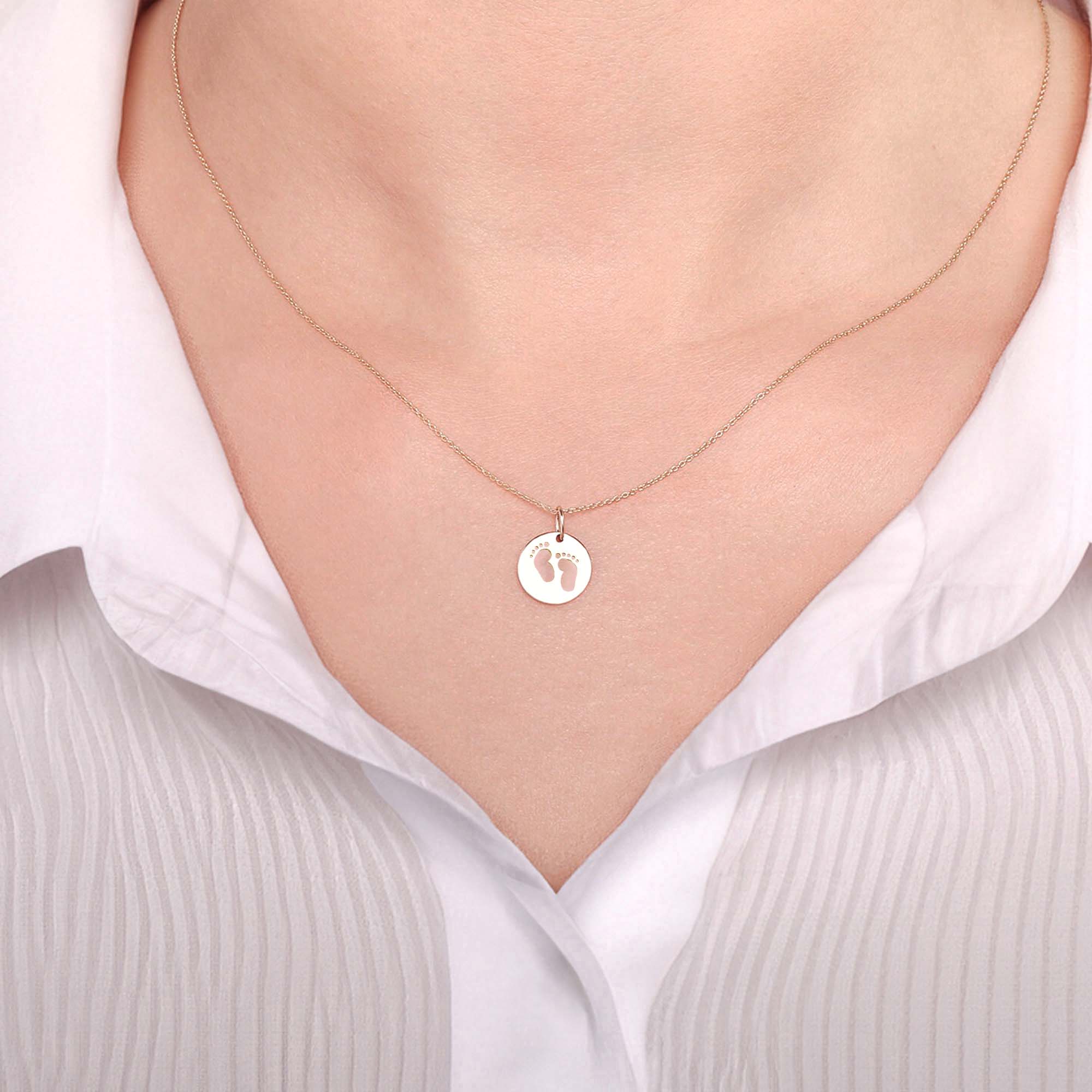 A 14k yellow gold babyfoot print pendant necklace on a model.