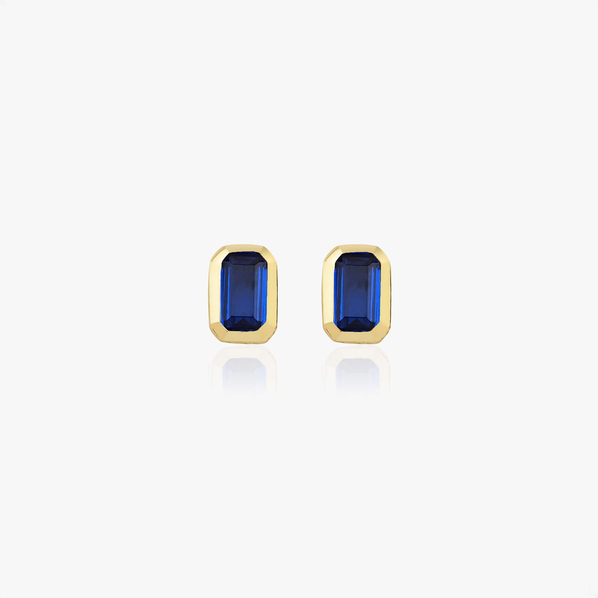 Gold earrings with blue gemstones on a white background