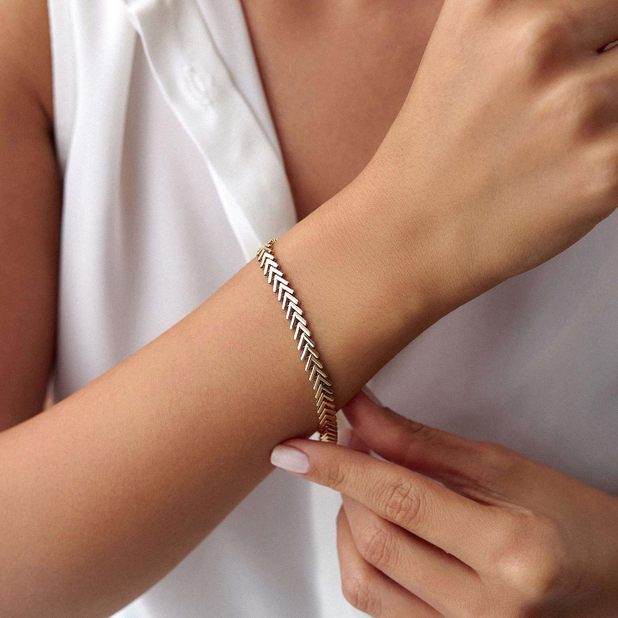 14k yellow gold chevron chain bracelet shown on a wrist.