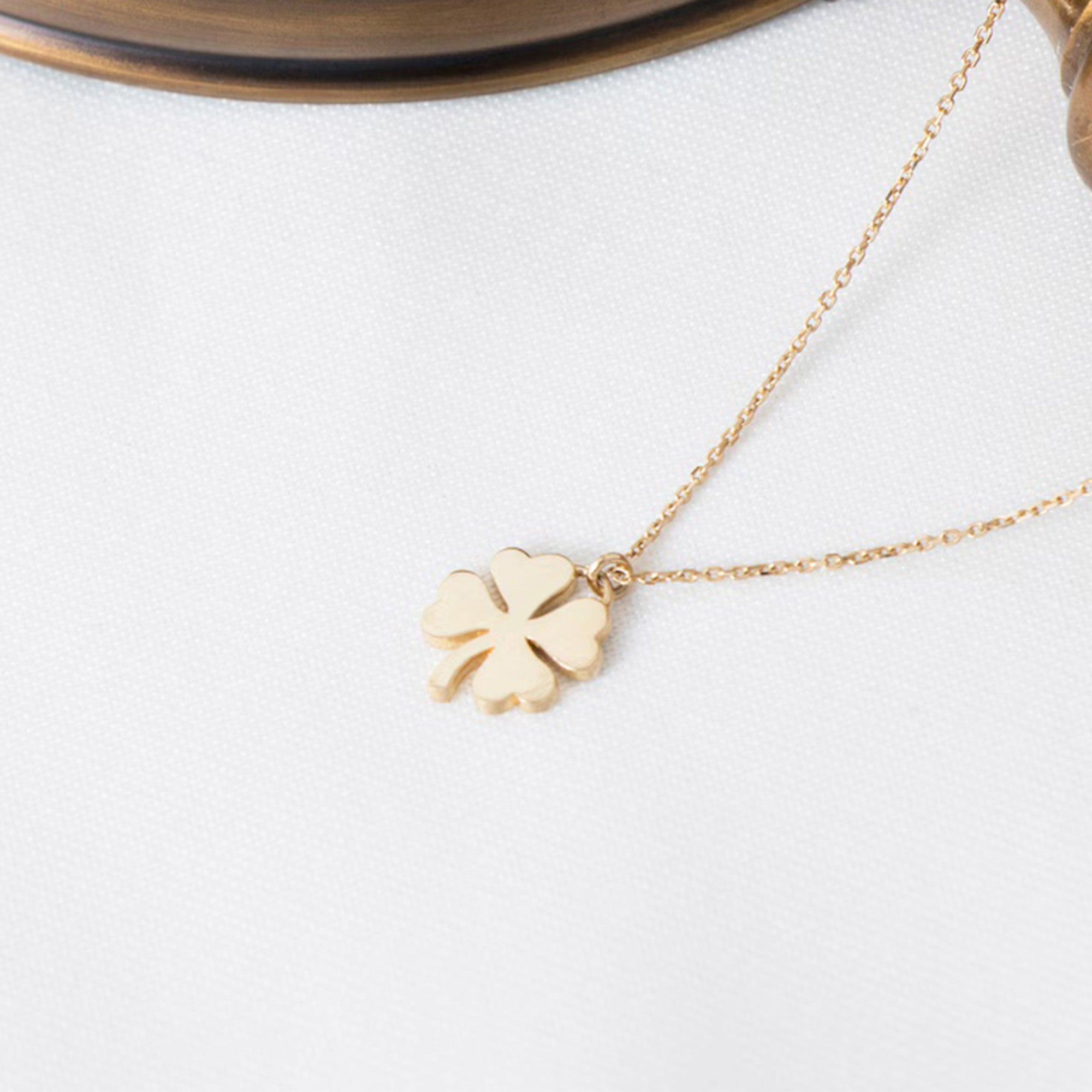 A 14K gold necklace with a four leaf clover pendant necklace on a white background.