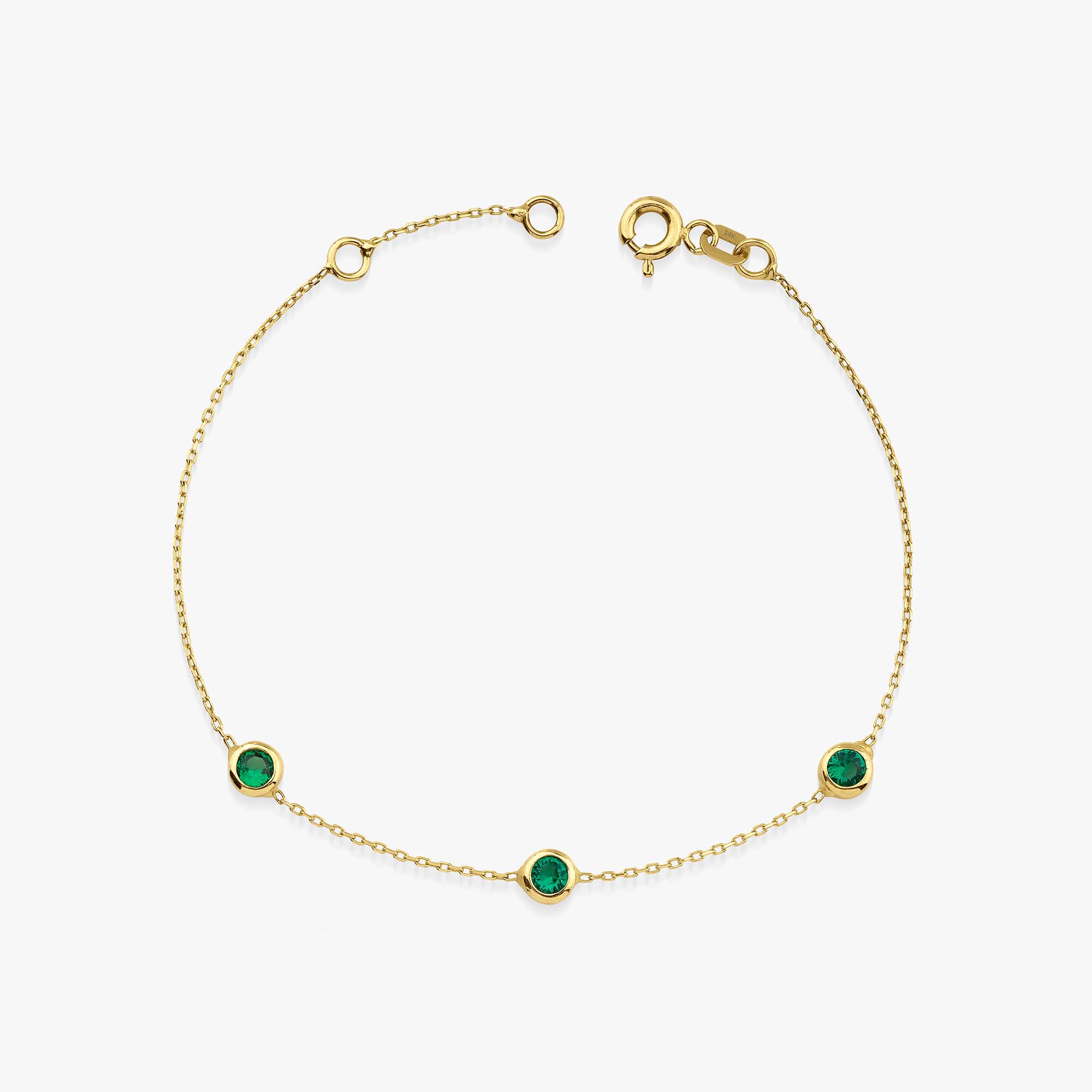 A created emerald bracelet in 14K yellow gold with a chain link and three bezel-set emeralds on the bracelet.