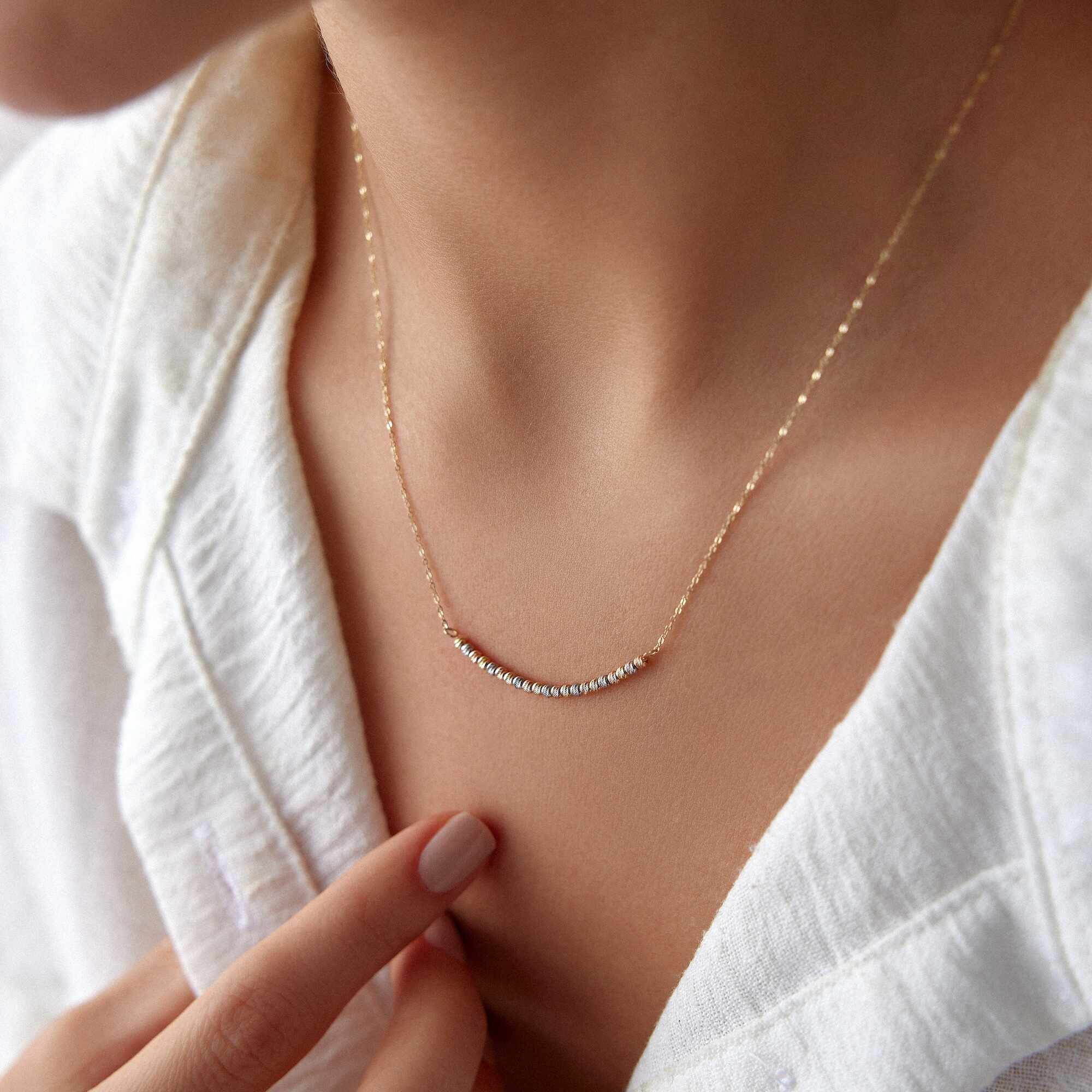 A model wearing a 14k gold curved bar necklace.