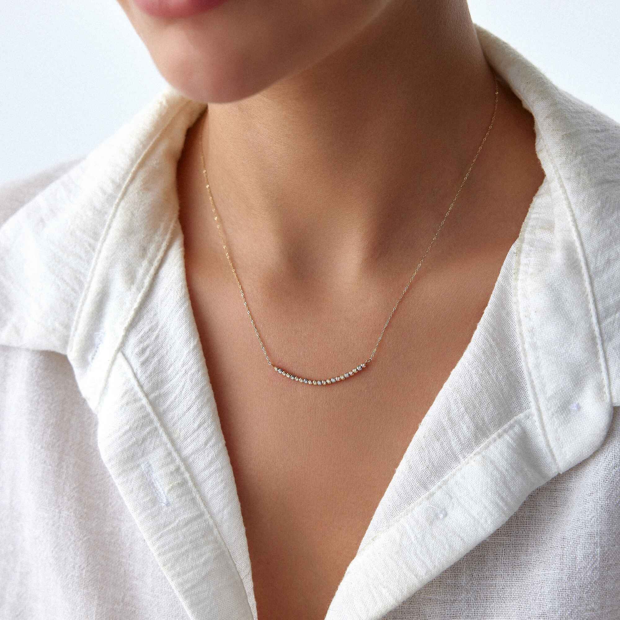 A model wearing a 14k gold curved bar necklace.