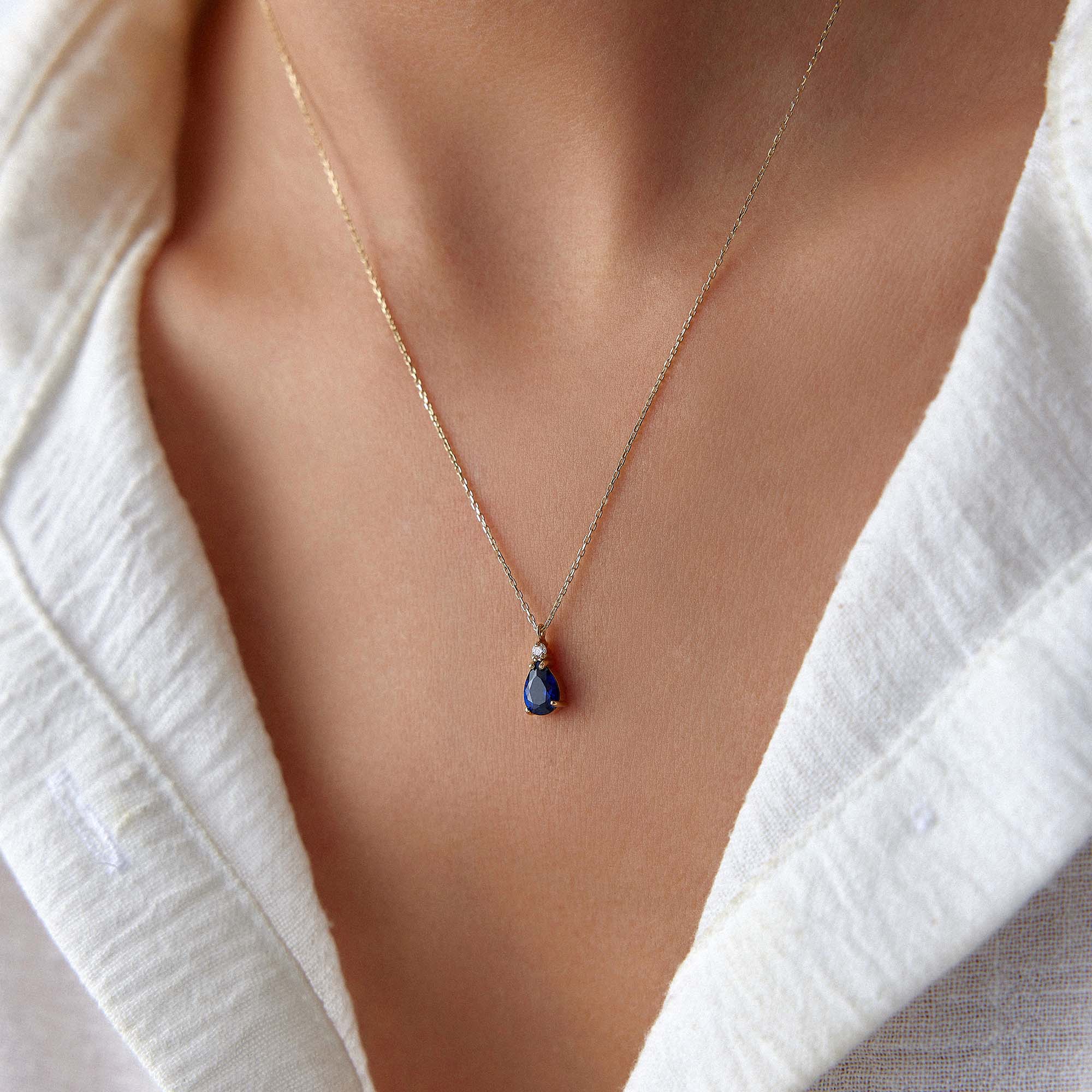 A model wearing a dark blue drop necklace.