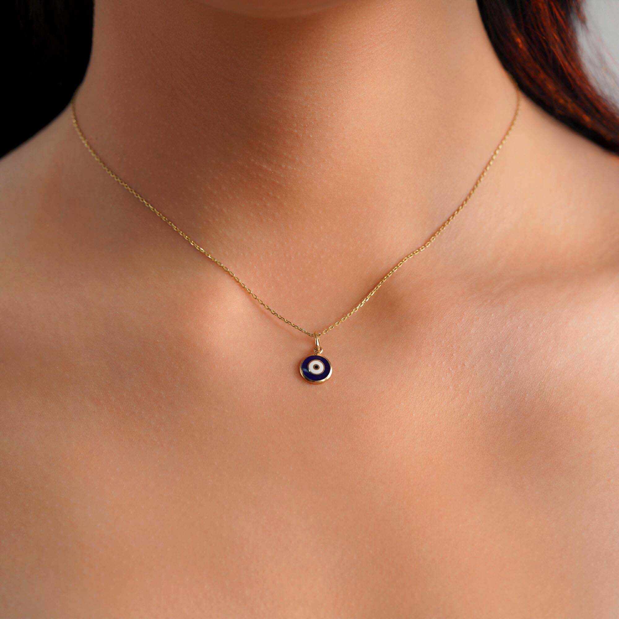 A model wearing an evil eye necklace with a dark blue evil eye center.