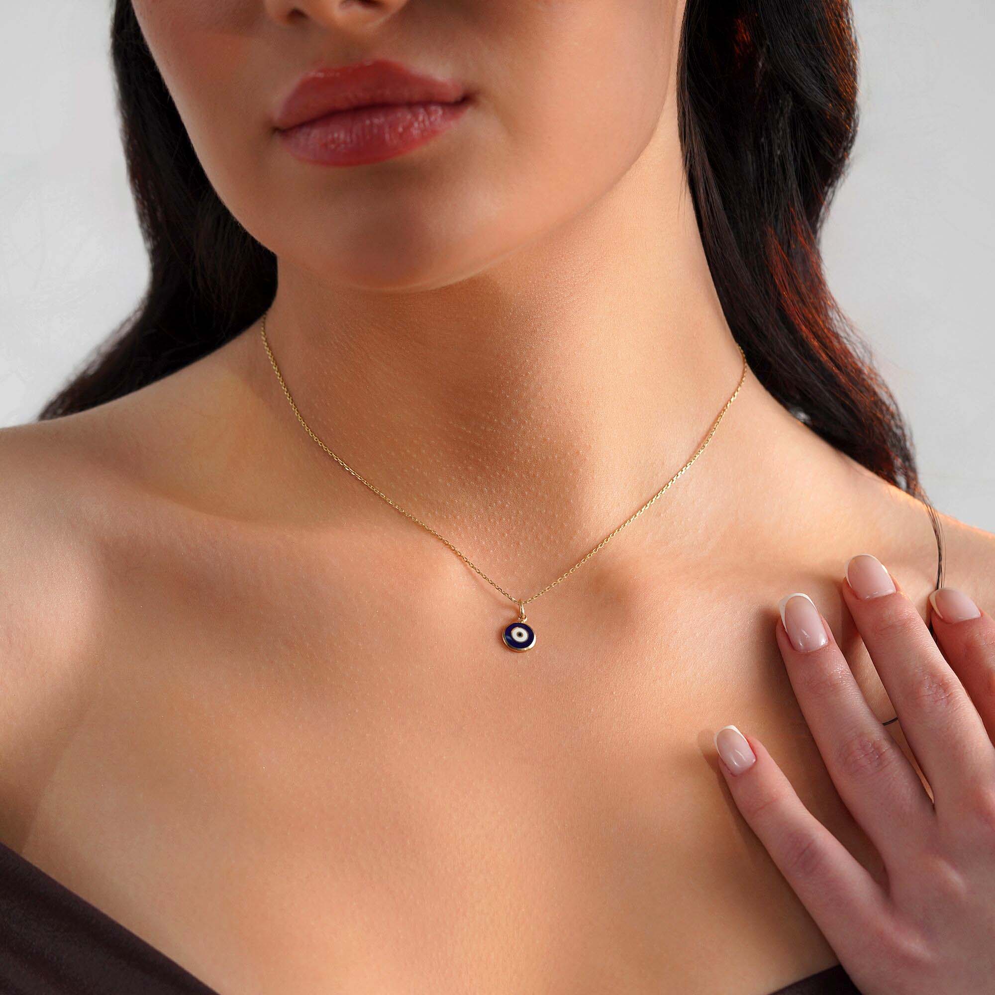 A model wearing an evil eye necklace with a dark blue evil eye center.