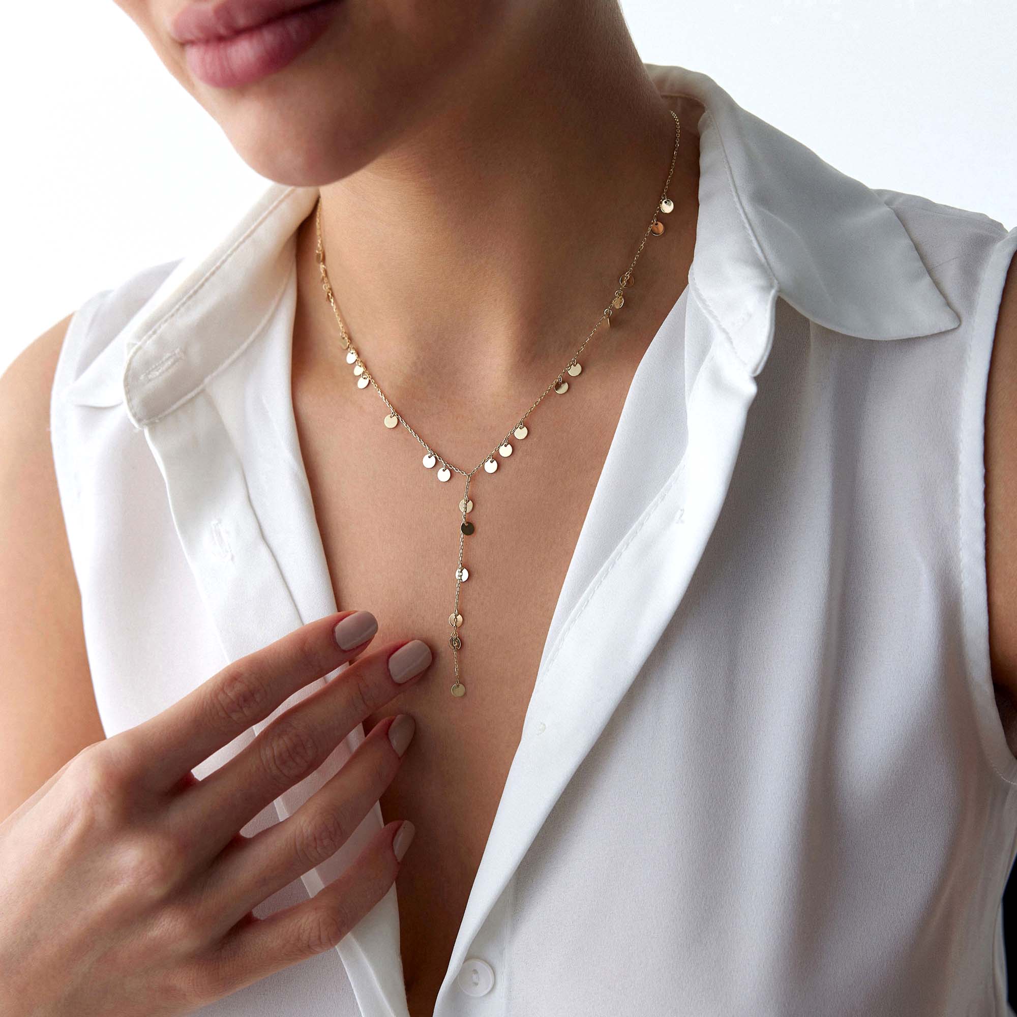 A model wearing a gold lariat necklace with dangling circle charms from the fine chain.