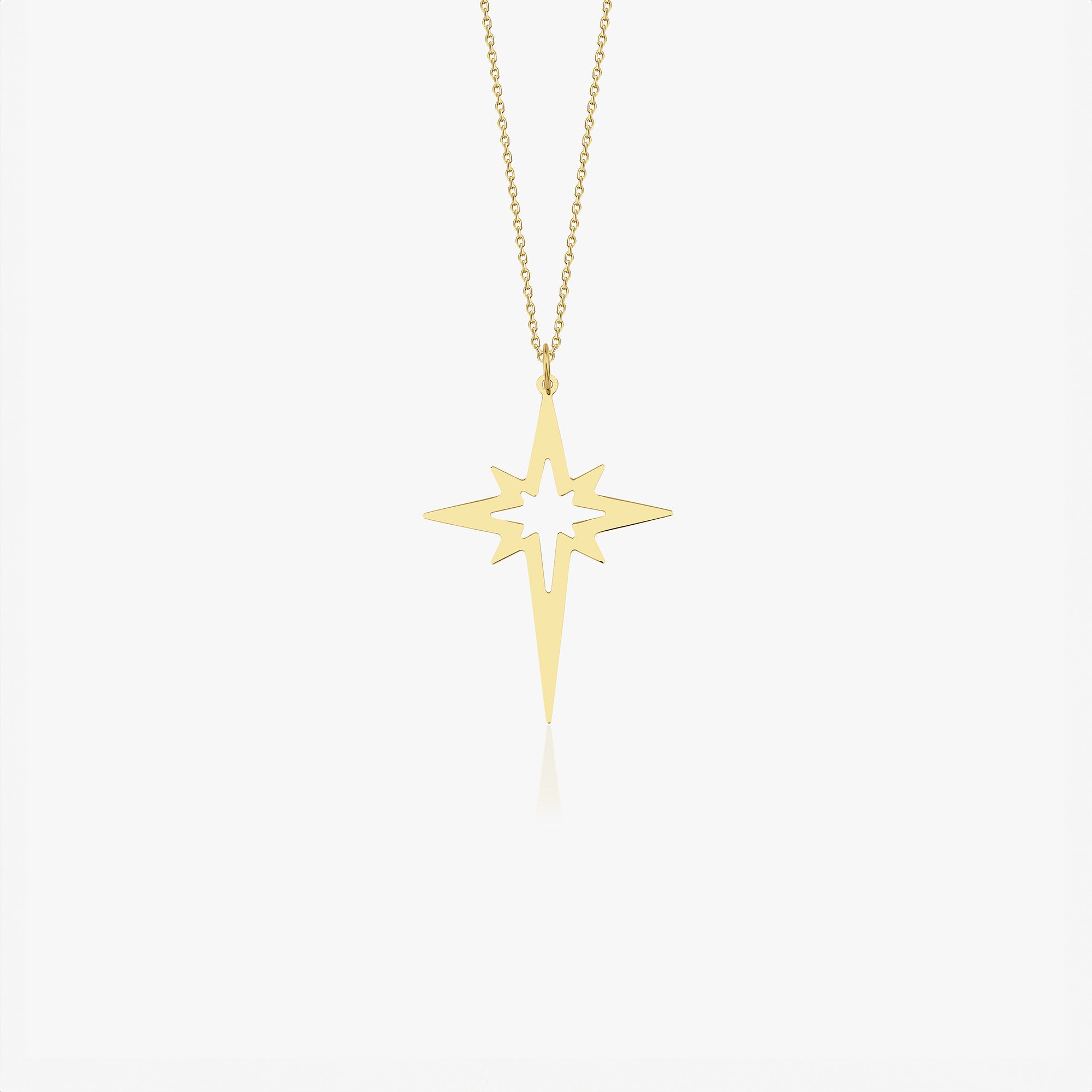 An elongated 14k yellow gold north star necklace shown on a white background.
