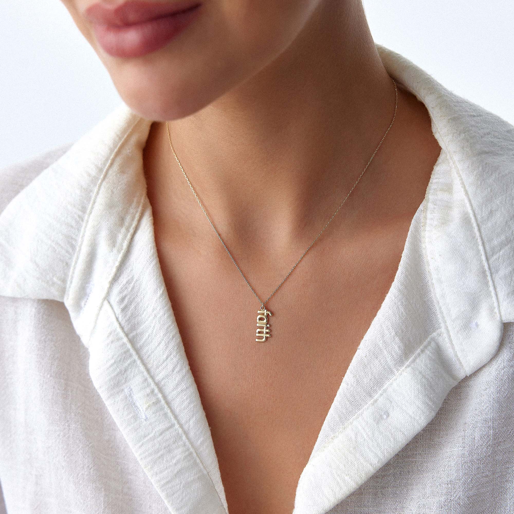 A model wearing a 14k yellow gold faith necklace.