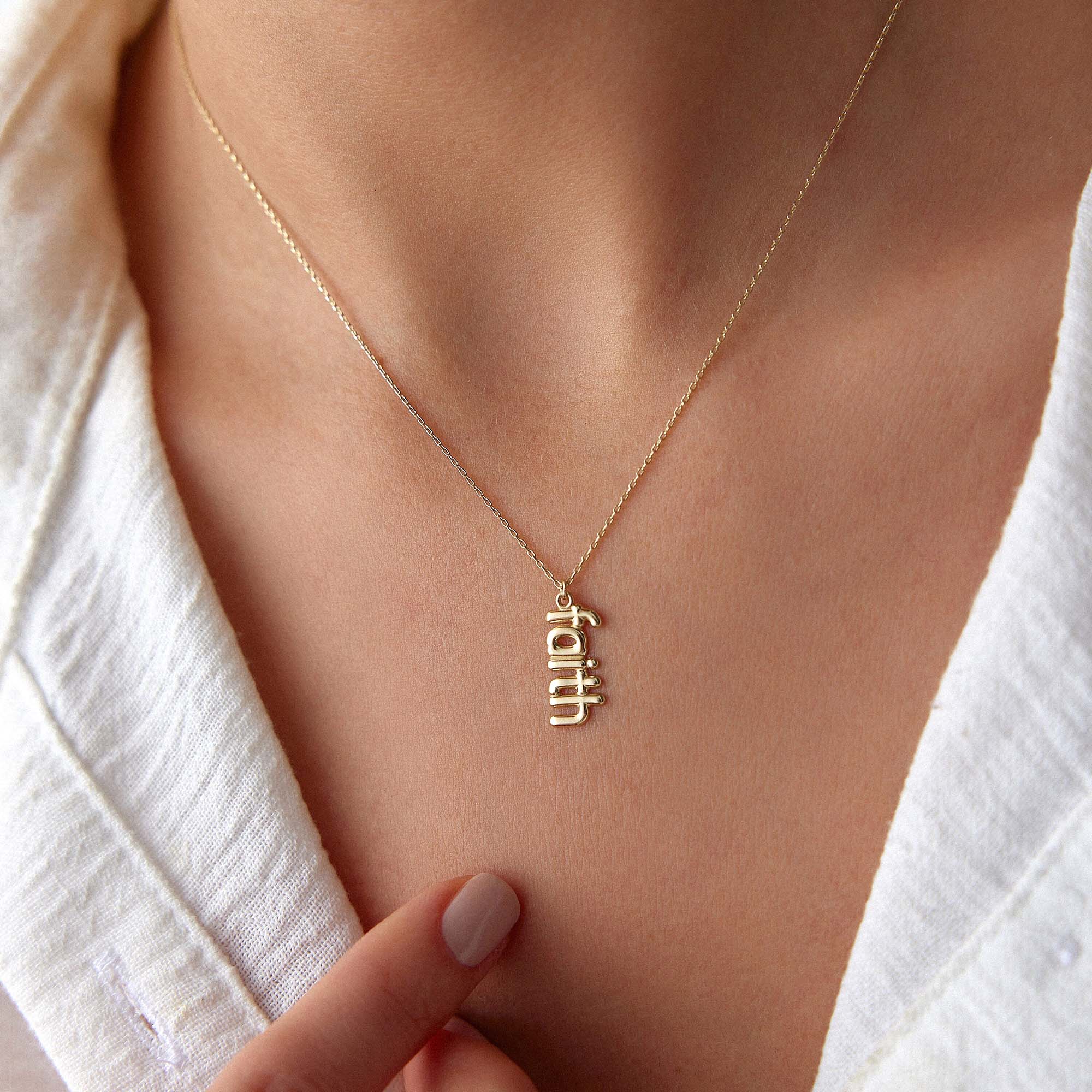 A model wearing a 14k yellow gold faith necklace.