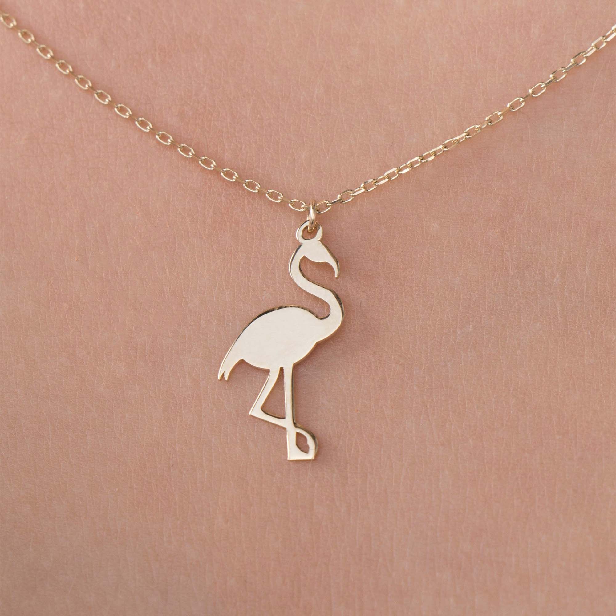 Gold flamingo pendant necklace on a model shown up-close