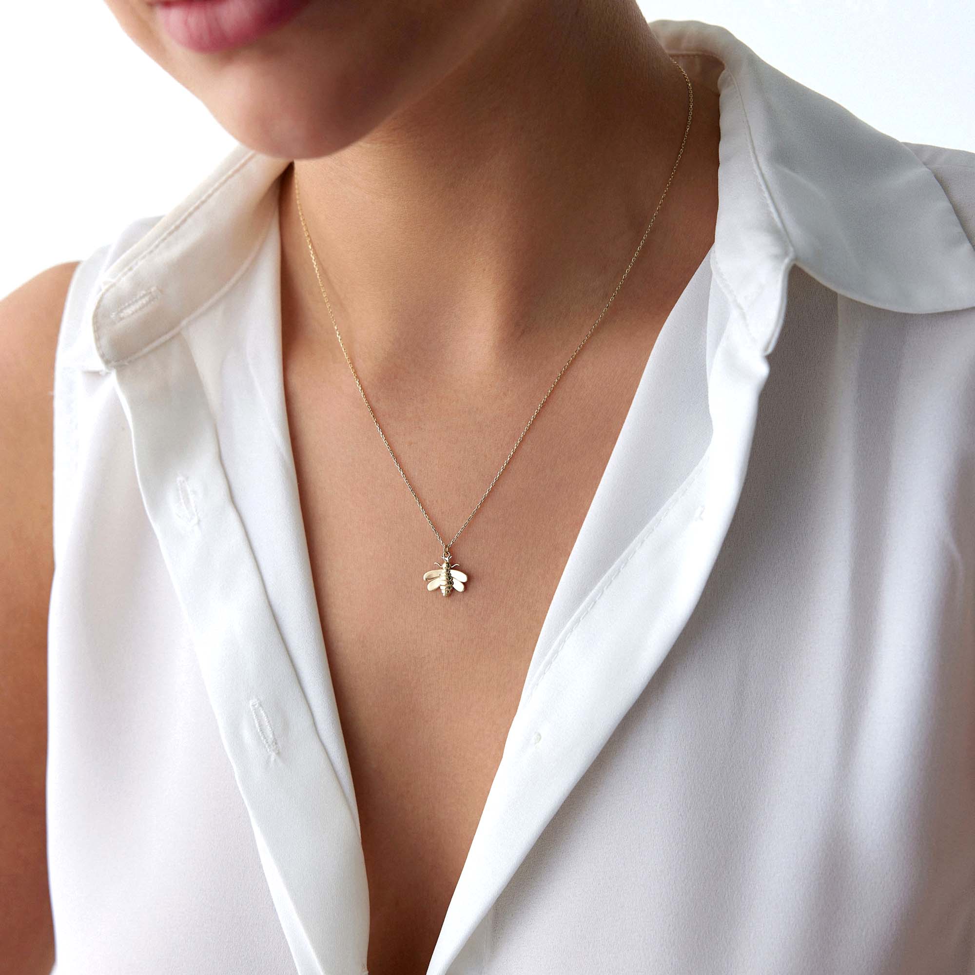 a model wearing a golden bee necklace