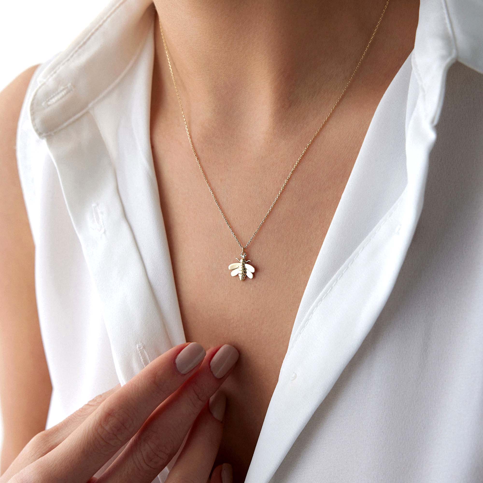 a model wearing a golden bee necklace