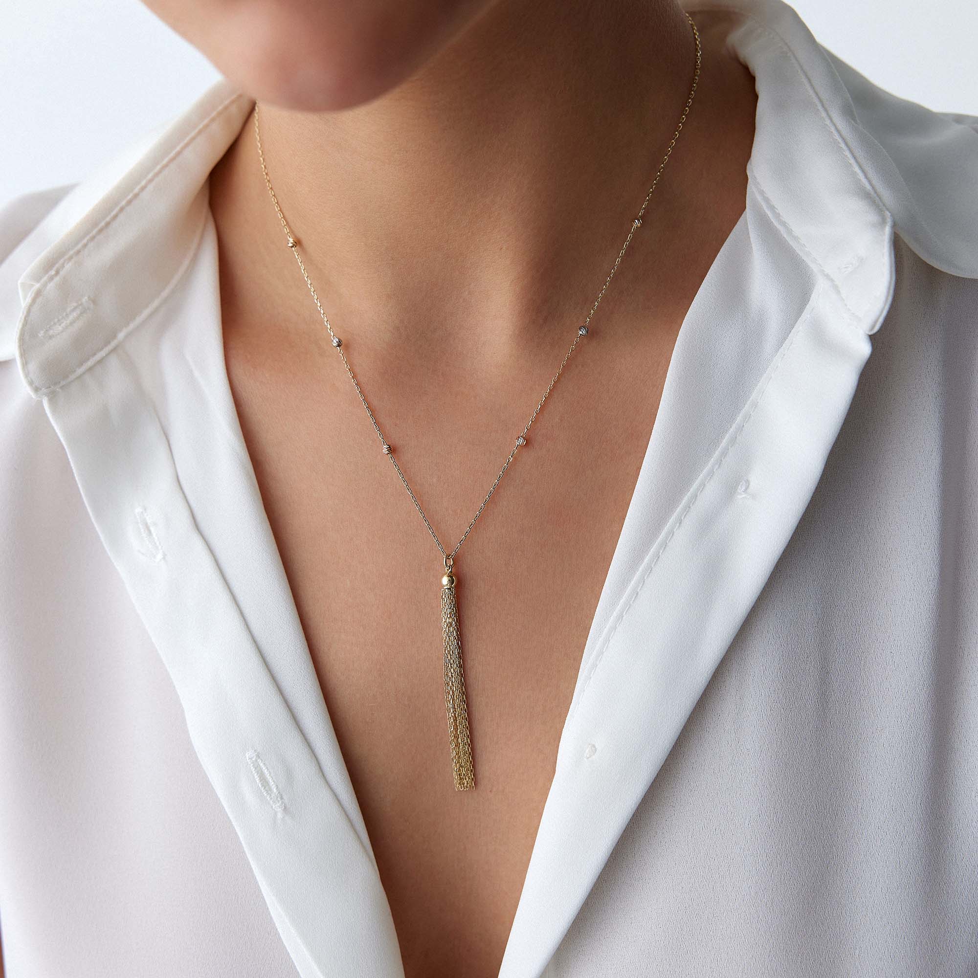 A model wearing a golden tassel necklace