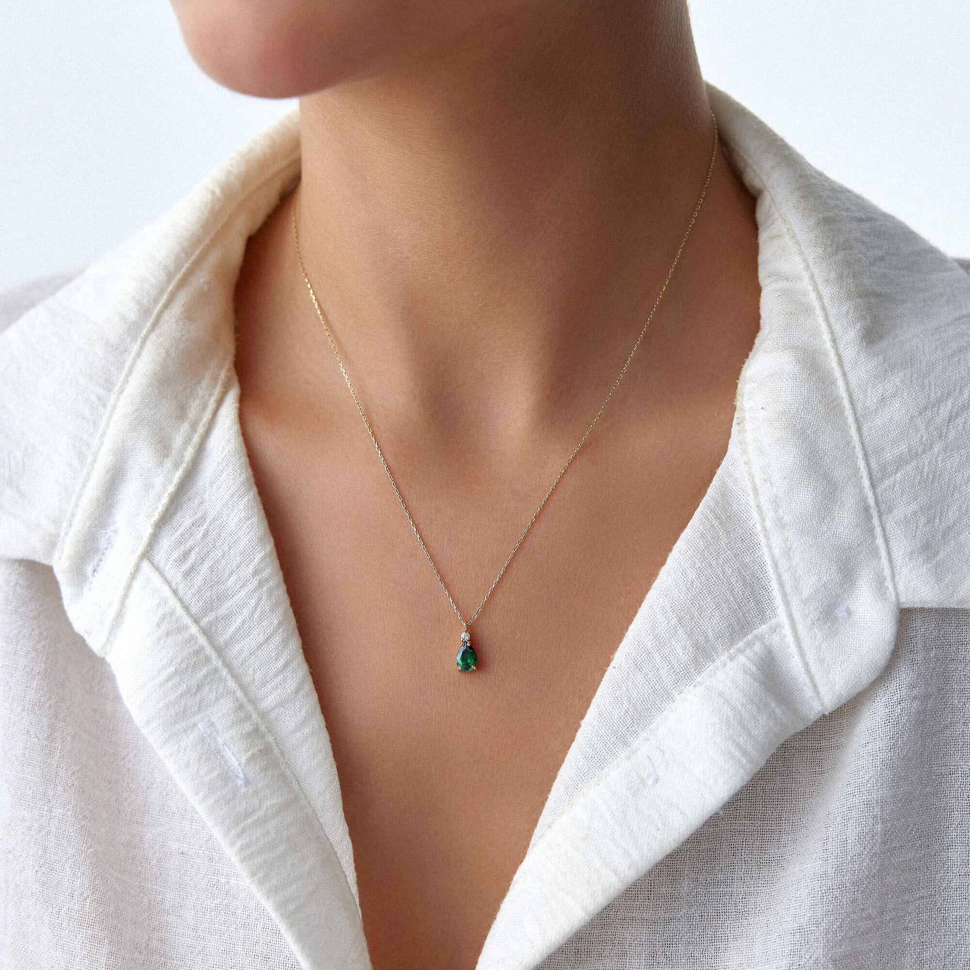 An image of a model wearing a green drop necklace