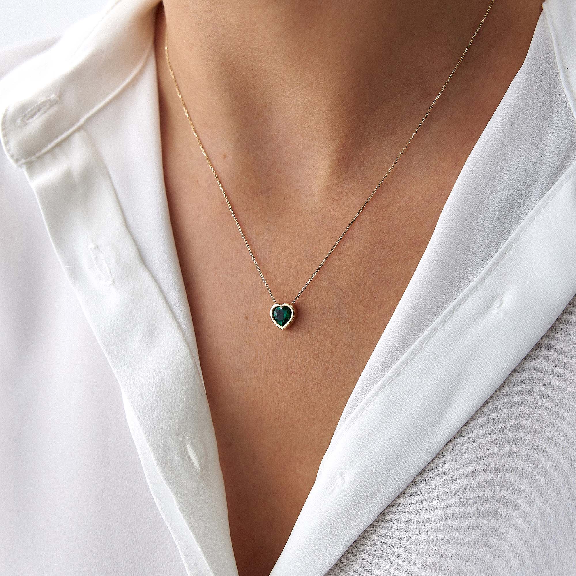 A model wearing a 14k yellow gold green heart necklace shown upclose