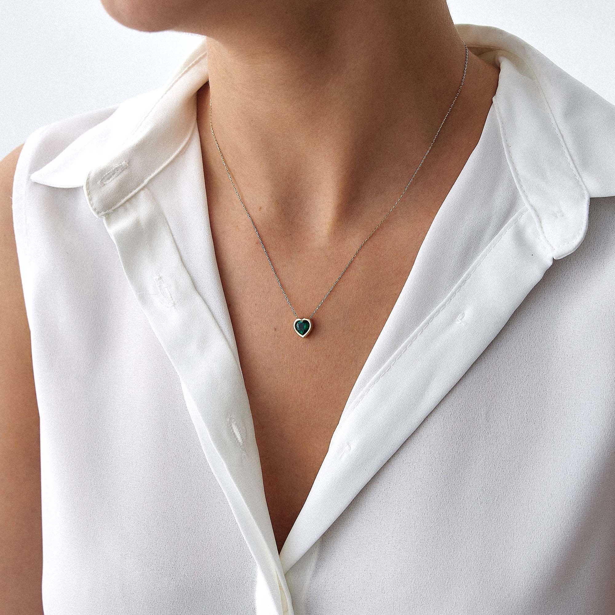 A model wearing a 14k yellow gold green heart necklace