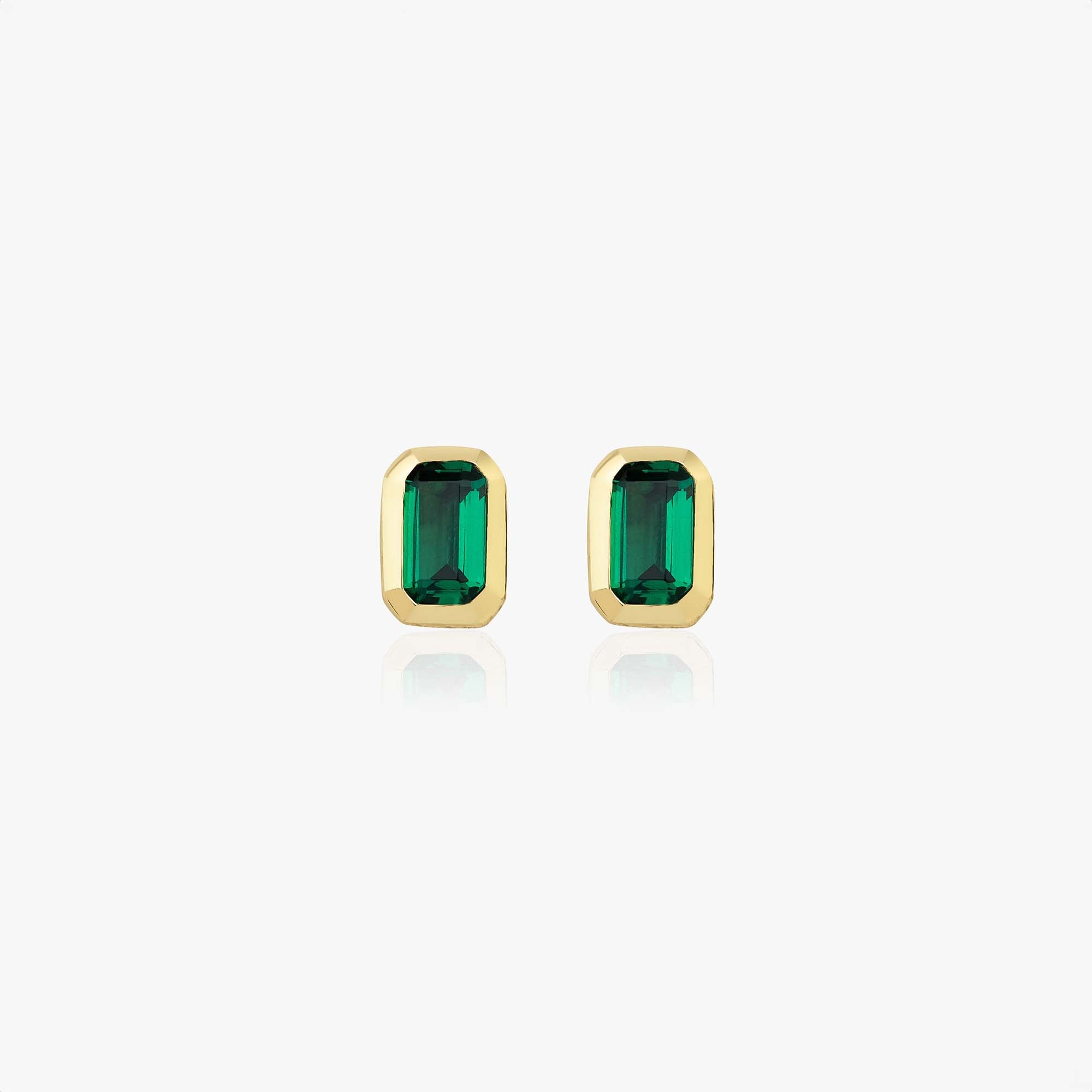 Gold earrings with green gemstones on a white background