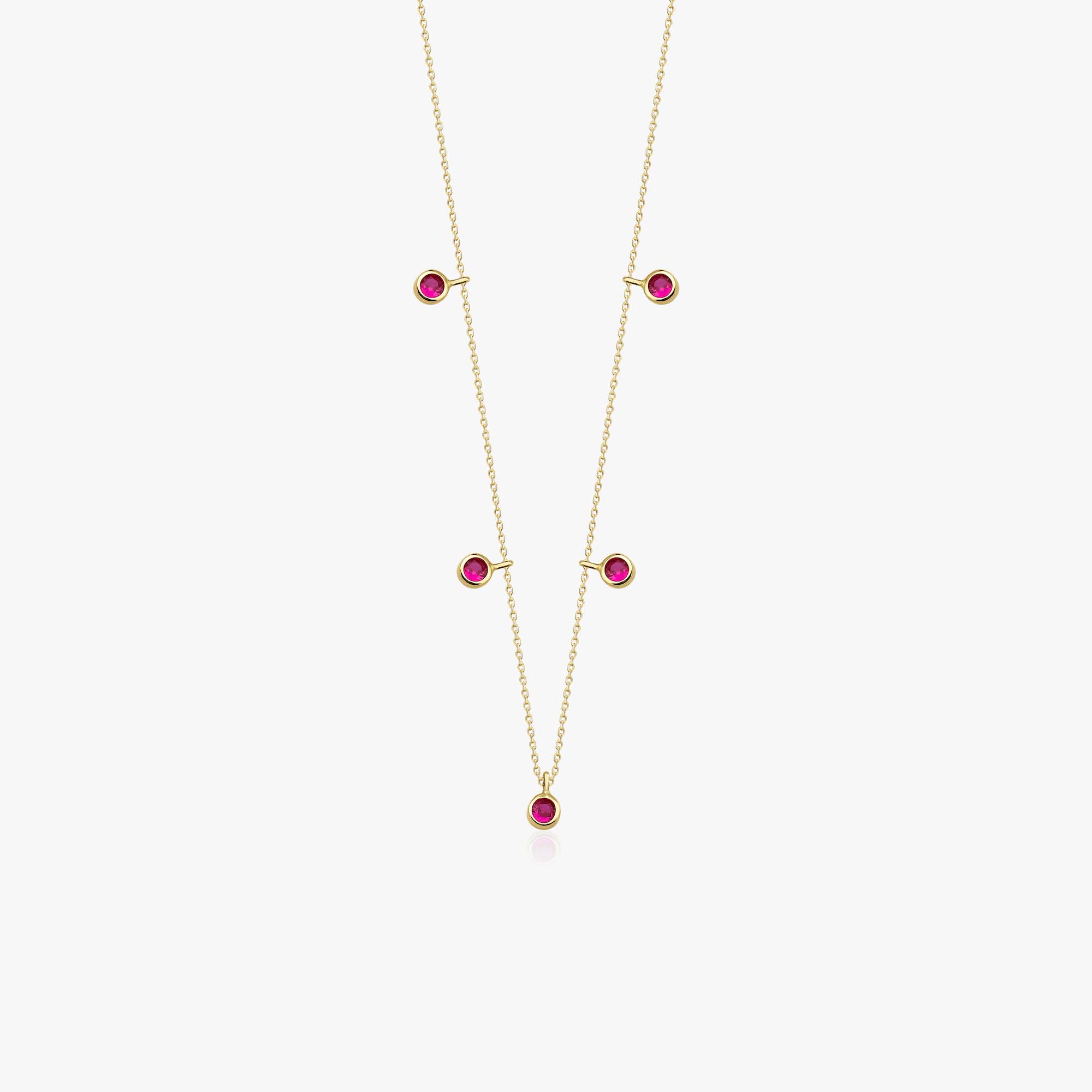 A 14k yellow gold dangle station necklace with lab rubies shown on a white background