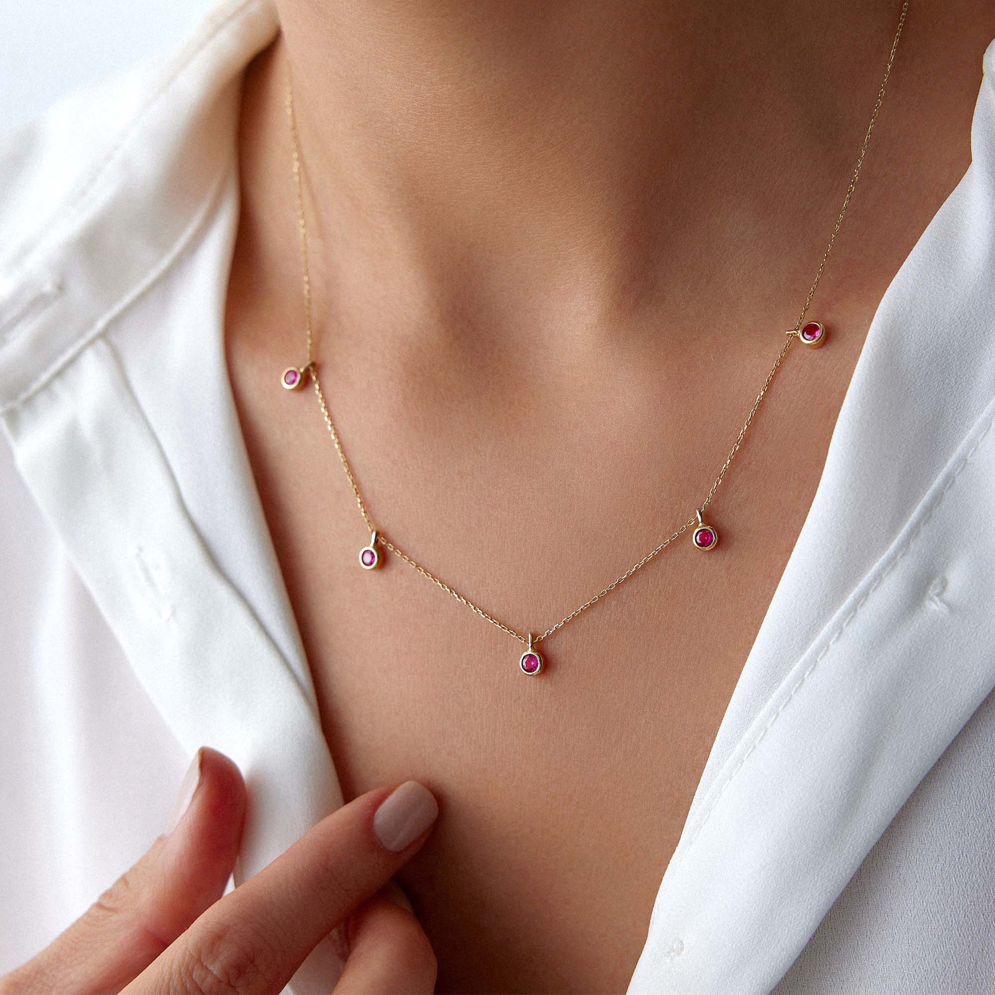 A model wearing a dangle station necklace with lab rubies