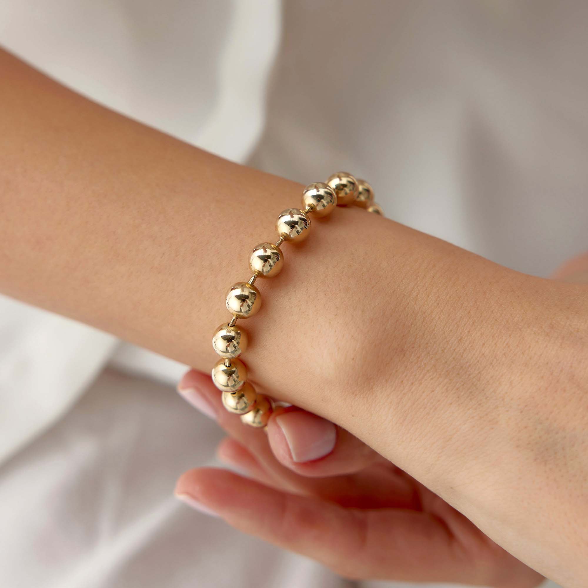 14k yellow gold large beaded bracelet shown in a wrist