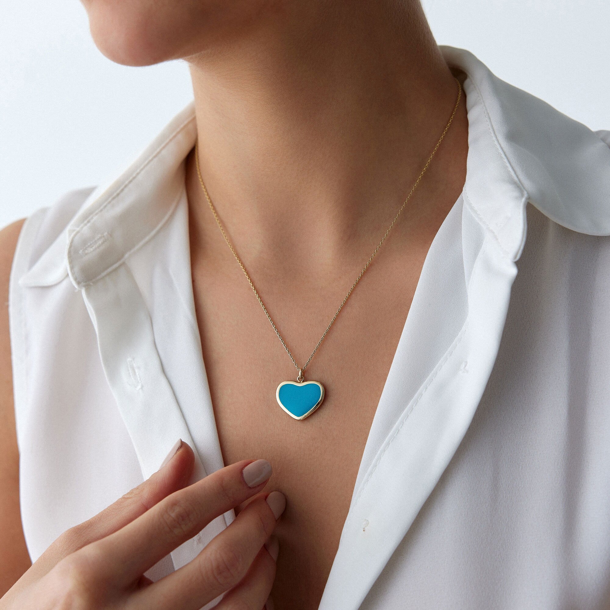 A model wearing a large ocean blue heart necklace shown up-lose.