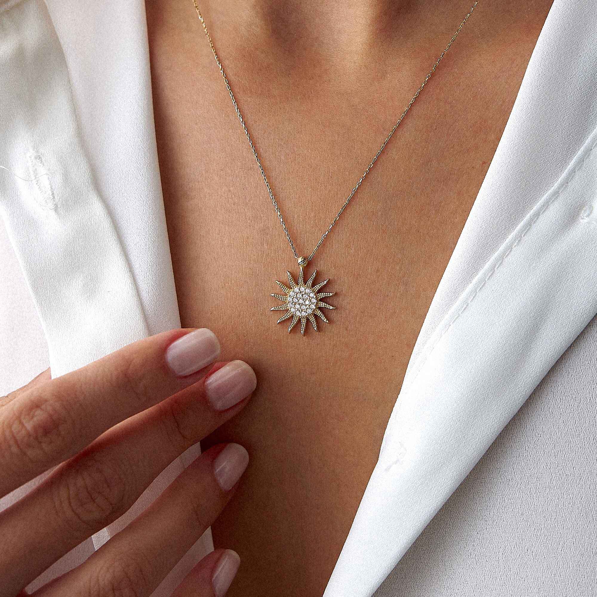 Sun-shaped necklace worn by a person with a white garment