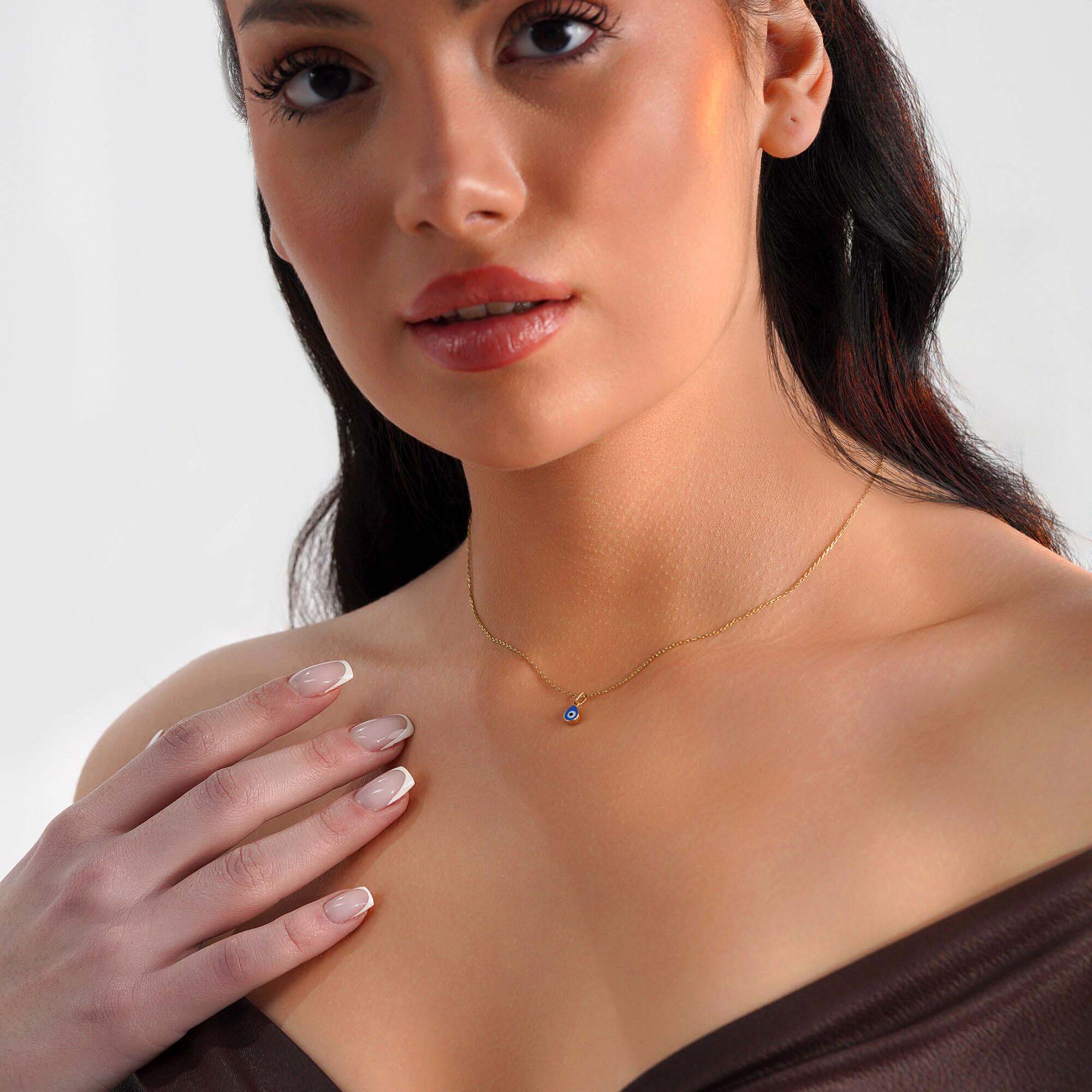 A model wearing a raindrop pendant necklace with an evil eye center.