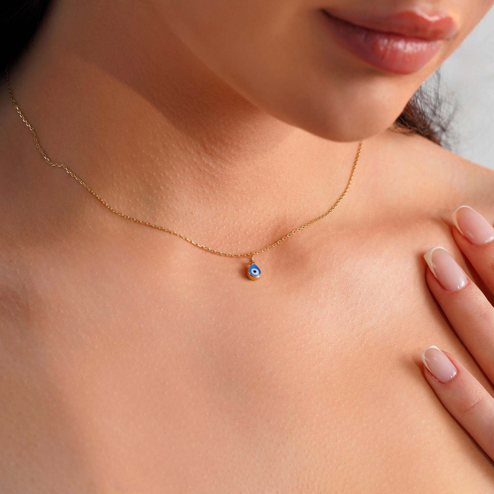 A model wearing a raindrop pendant necklace with an evil eye center.