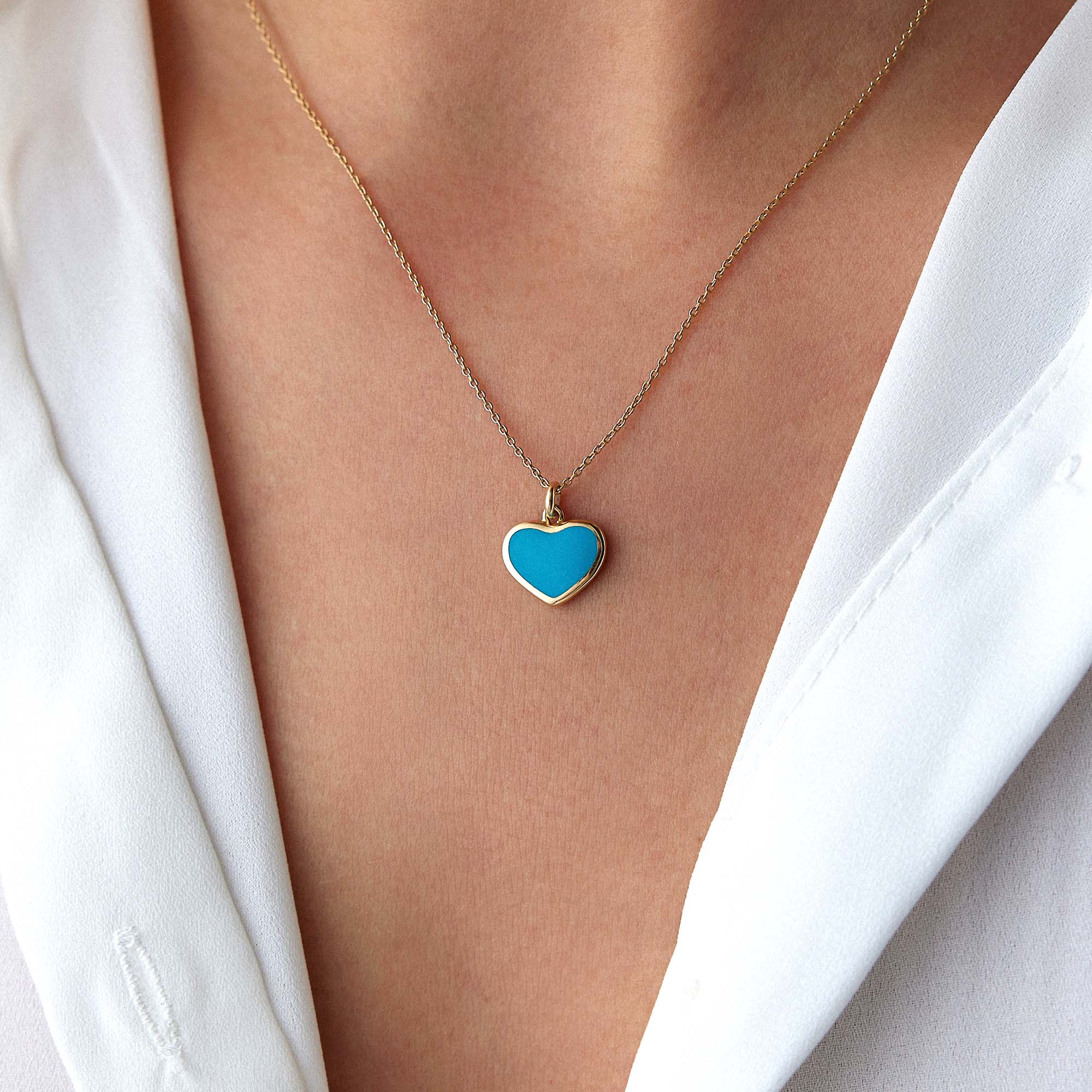 A model wearing an ocean blue heart pendant on a thin chain.