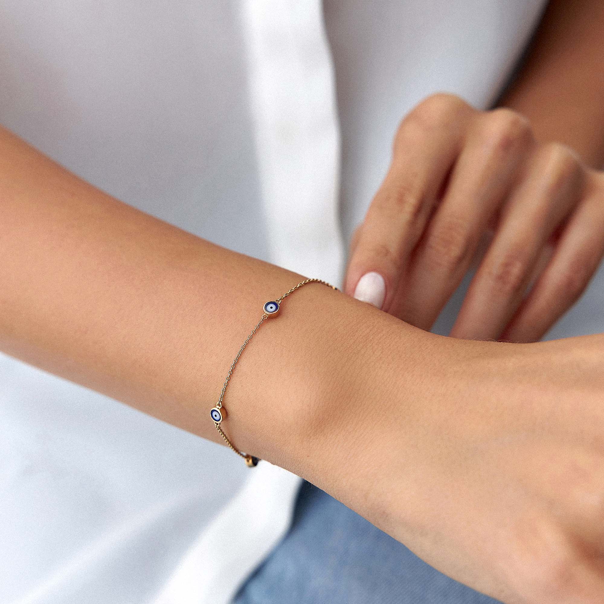 14k yellow gold navy blue evil eye bracelet with 5 evil eyes shown on a wrist