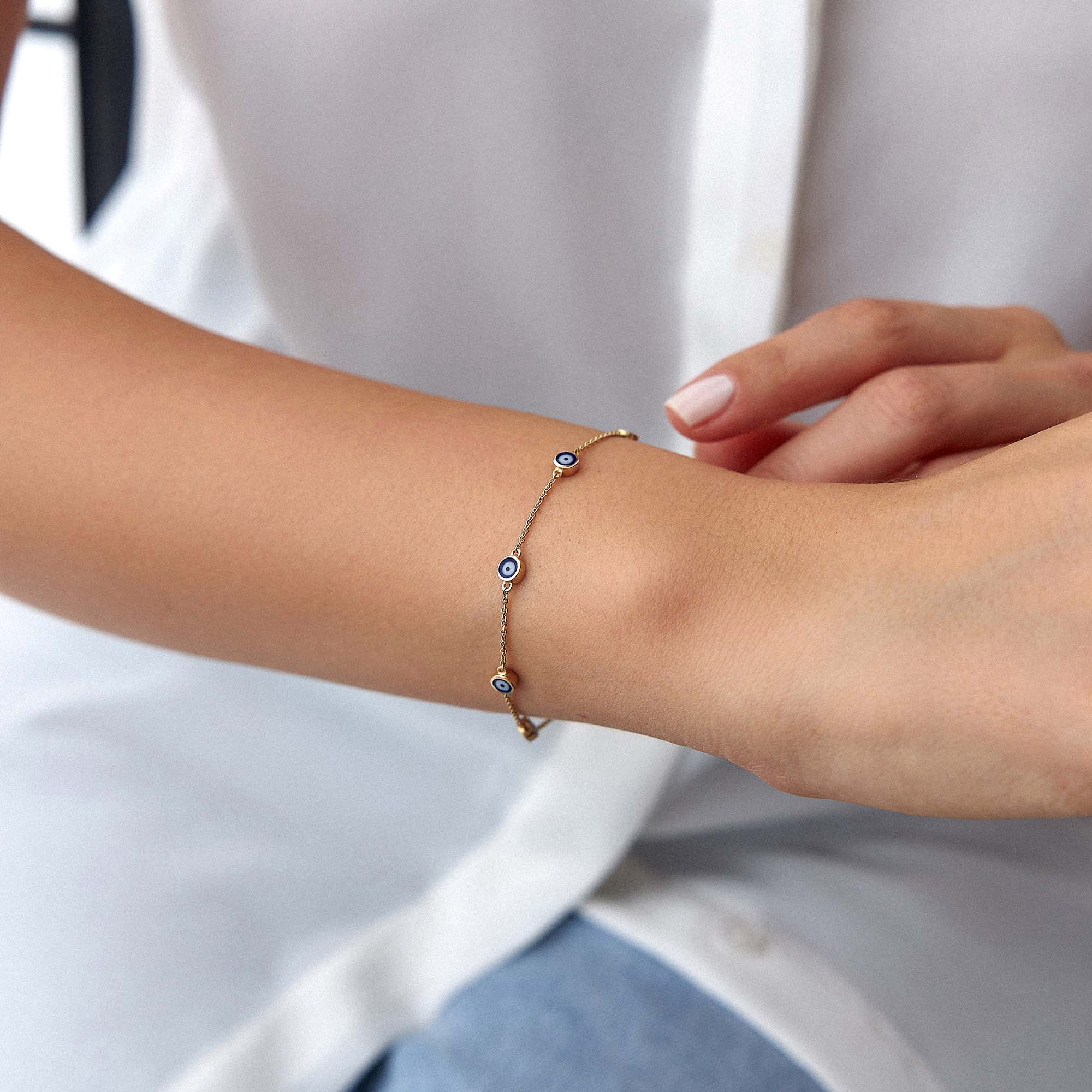 14k yellow gold navy blue evil eye bracelet with 7 evil eyes shown on a wrist