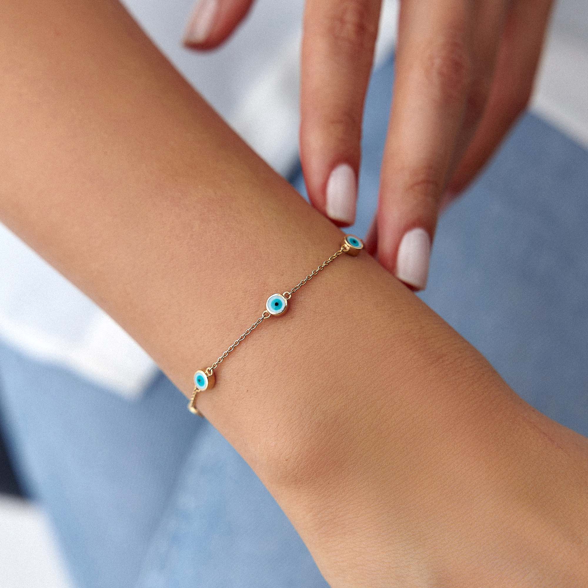14k yellow gold evil eye bracelet with 7 white evil eyes shown on a wrist