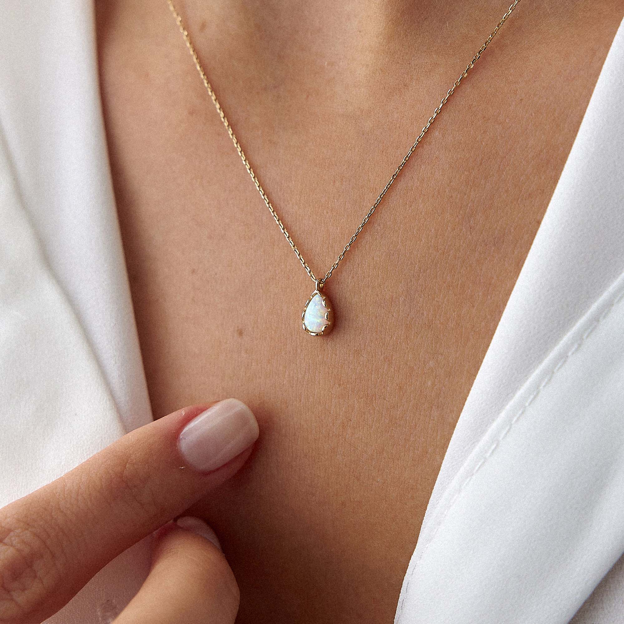 An up-close image of a model wearing a raindrop shaped opal necklace.