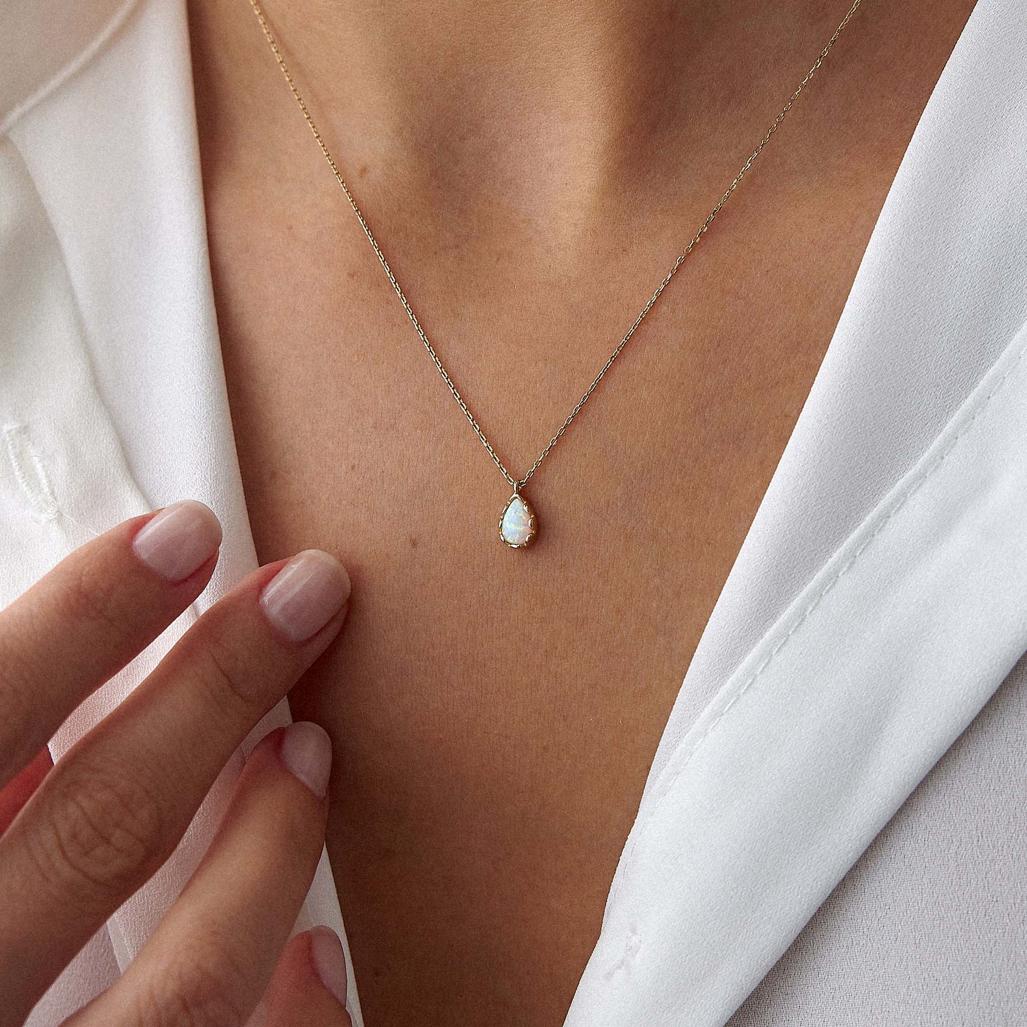 An up-close image of a model wearing a raindrop shaped opal necklace.