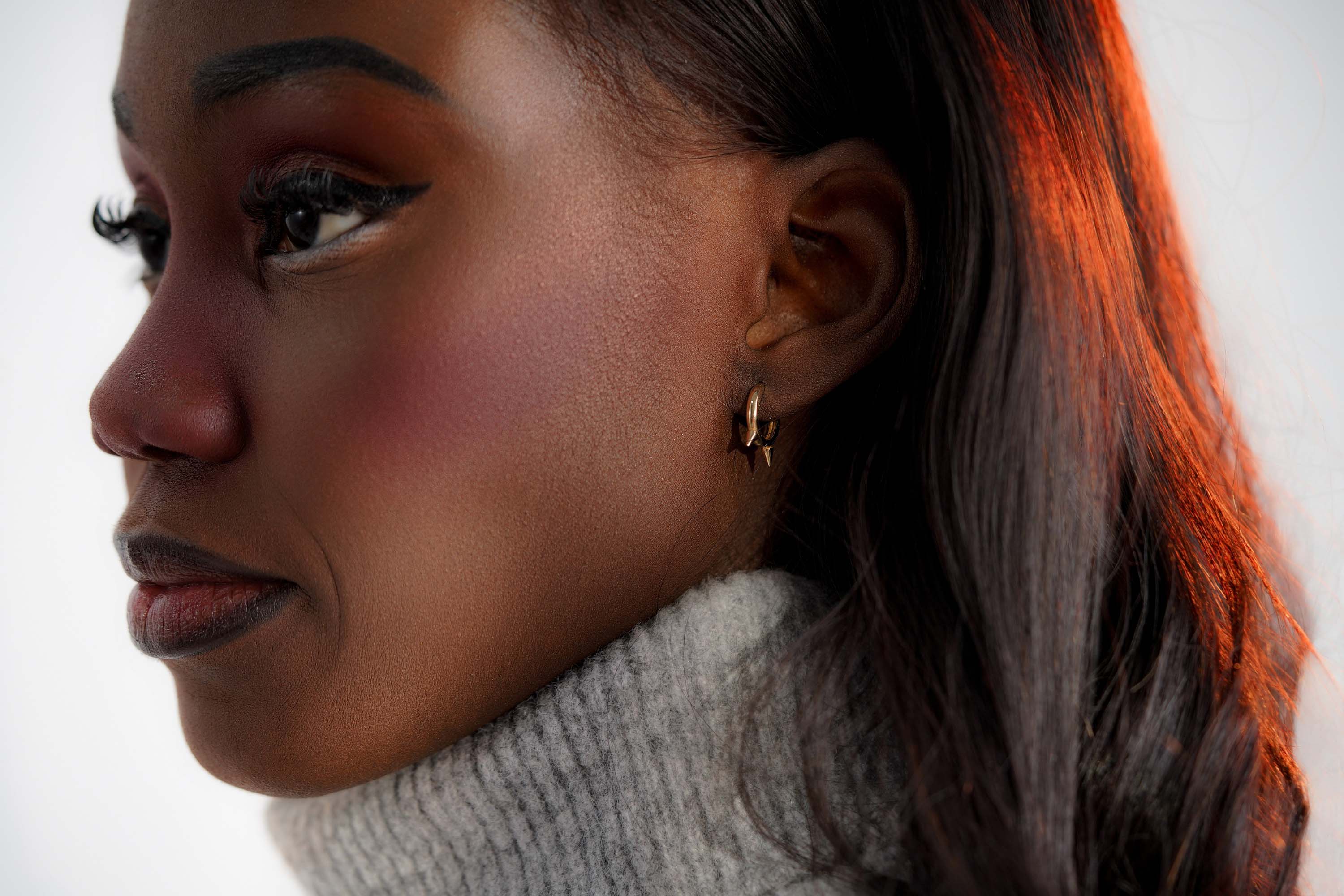 Close-up of a person wearing a gold hoop with golden spikes.