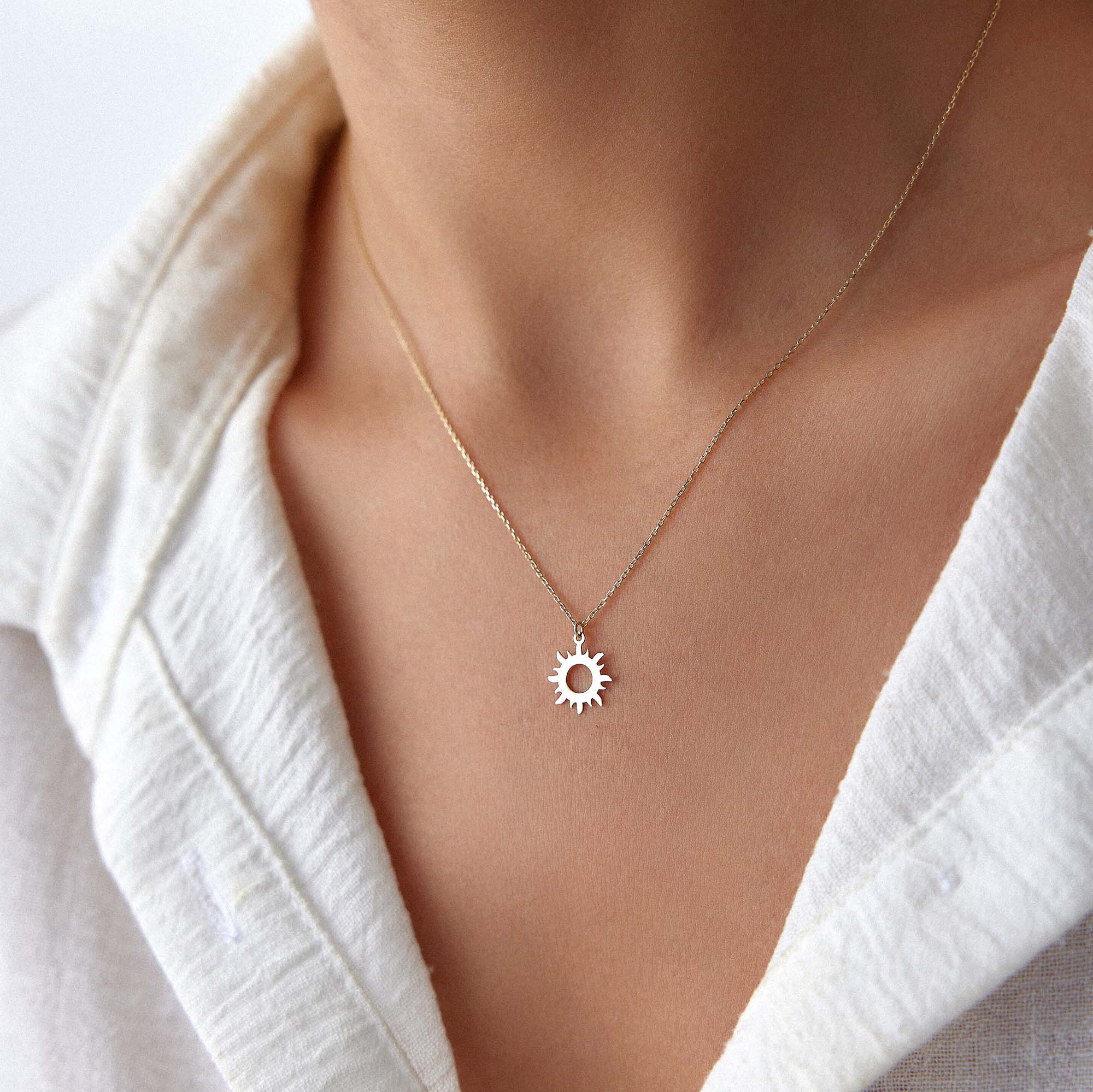 An image of a model wearing a minimal sun pendant necklace.