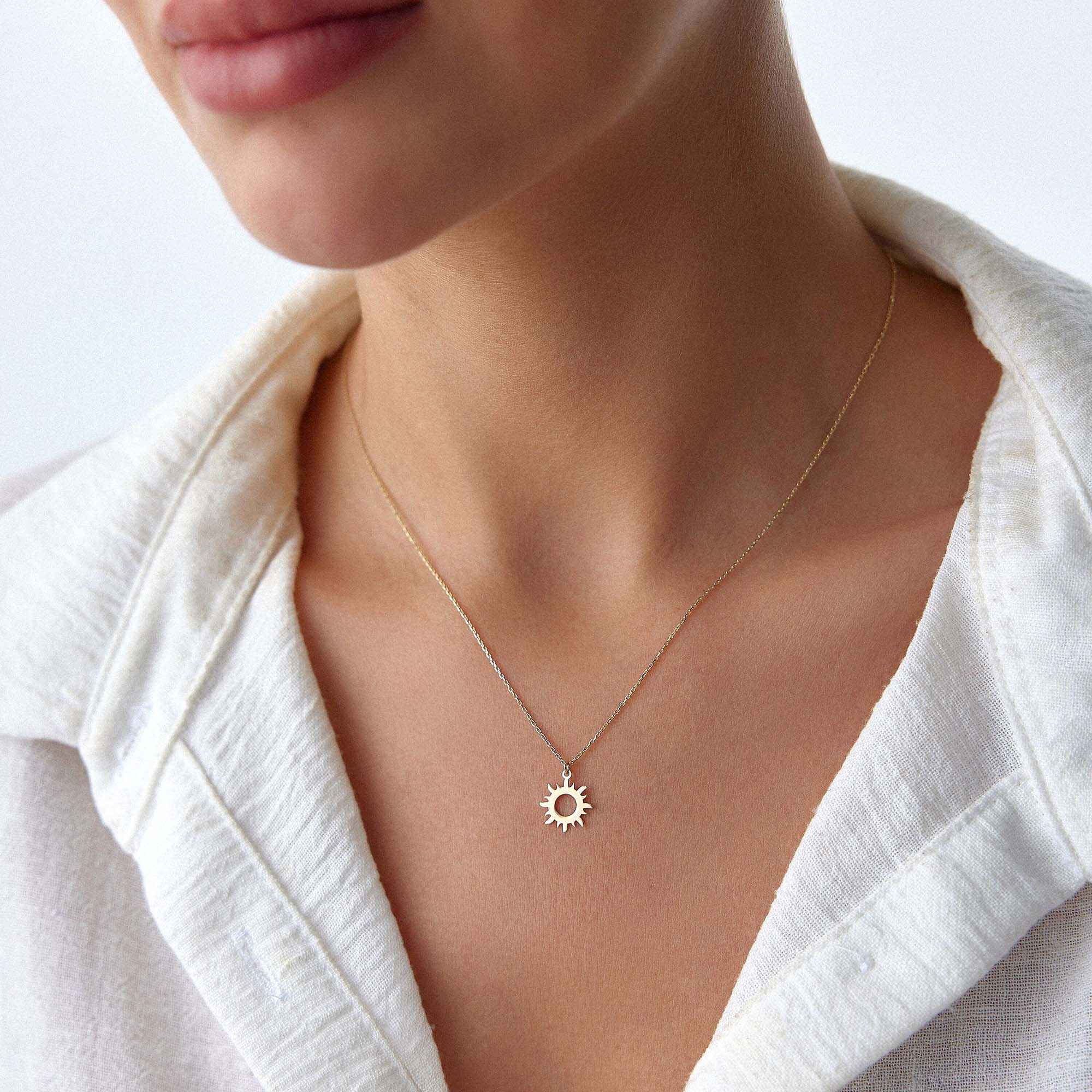 An image of a model wearing a minimal sun pendant necklace.