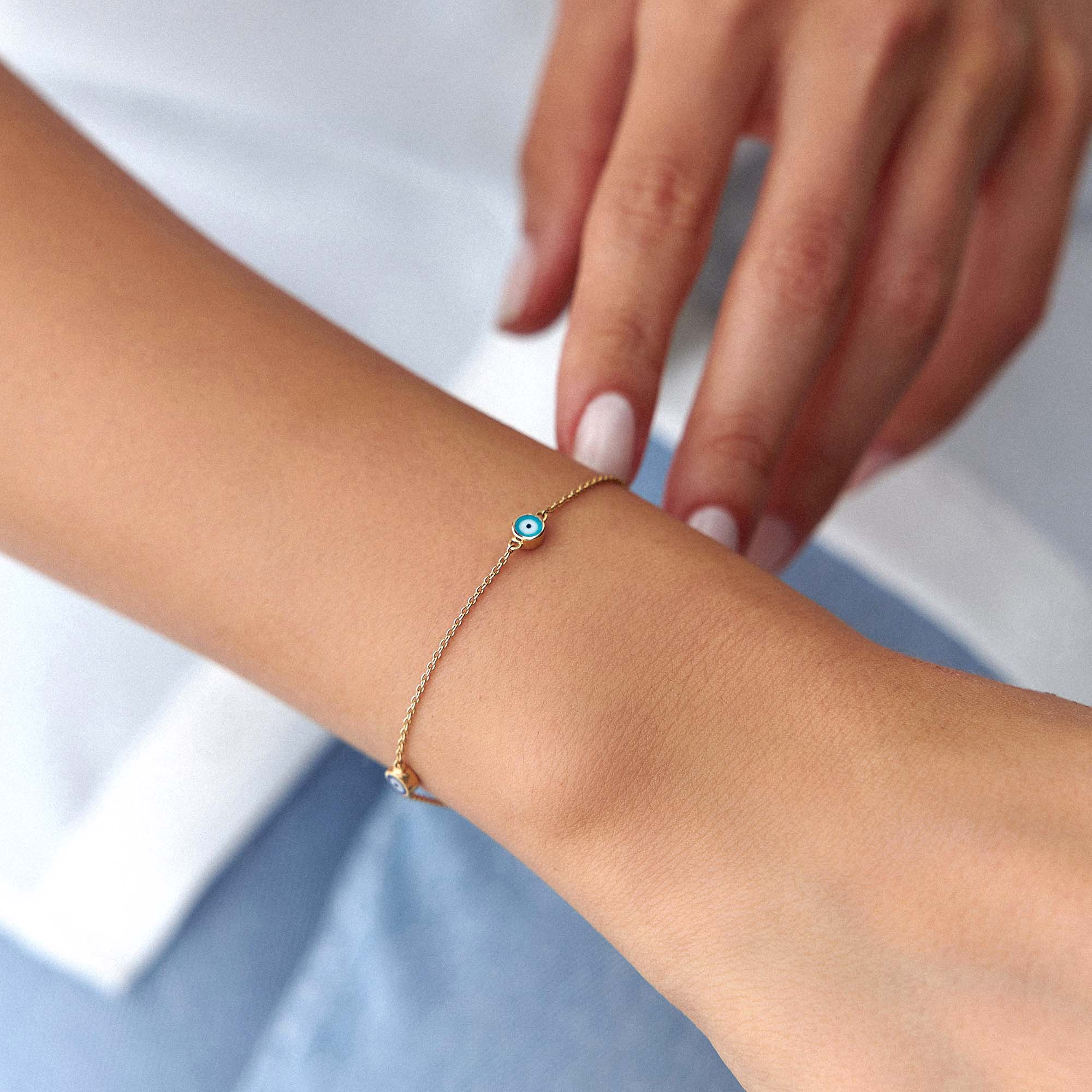 14 karat yellow gold multicolor evil eye bracelet with three evil eyes on a wrist