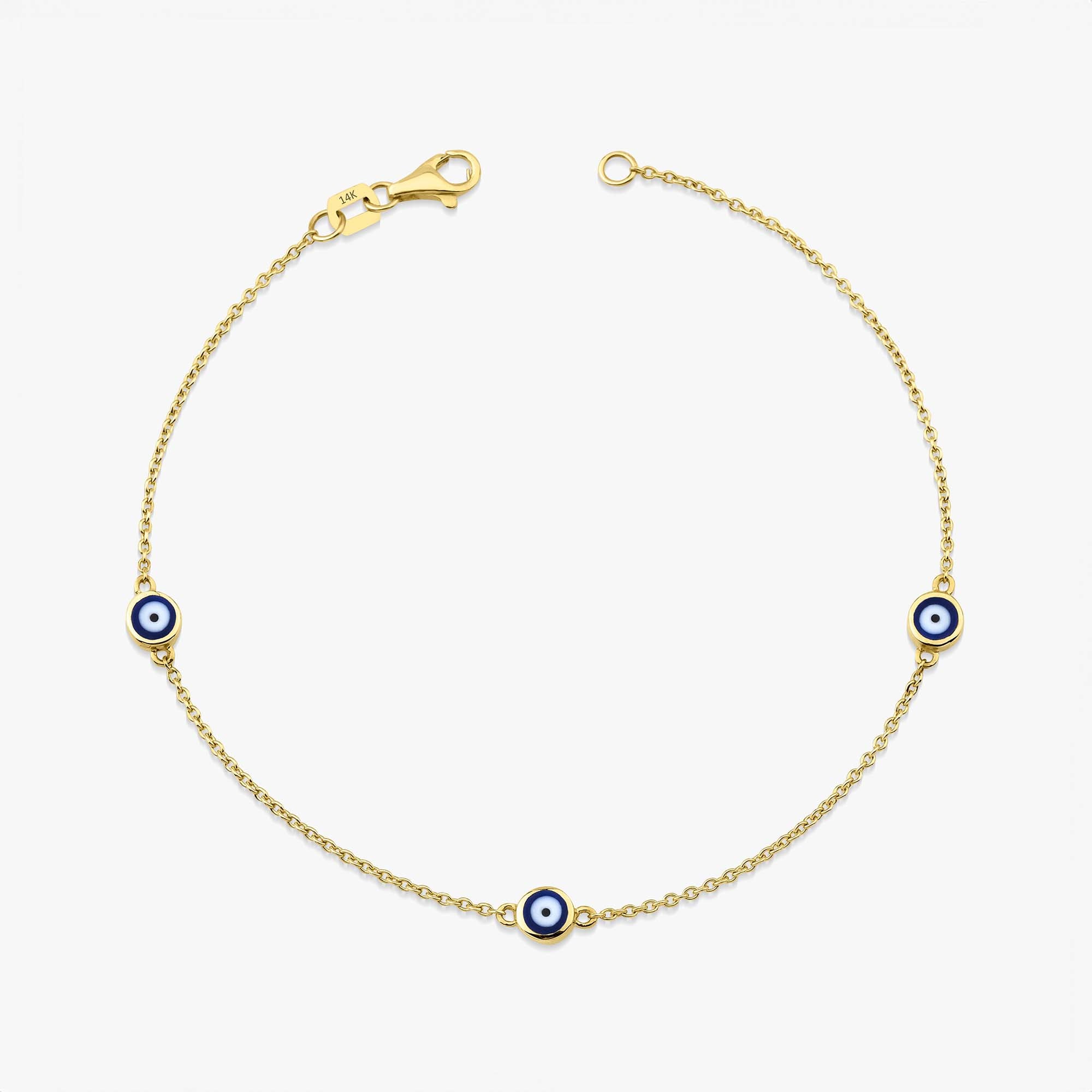 A 14 karat yellow gold bracelet with three navy blue evil eye charms on a white background