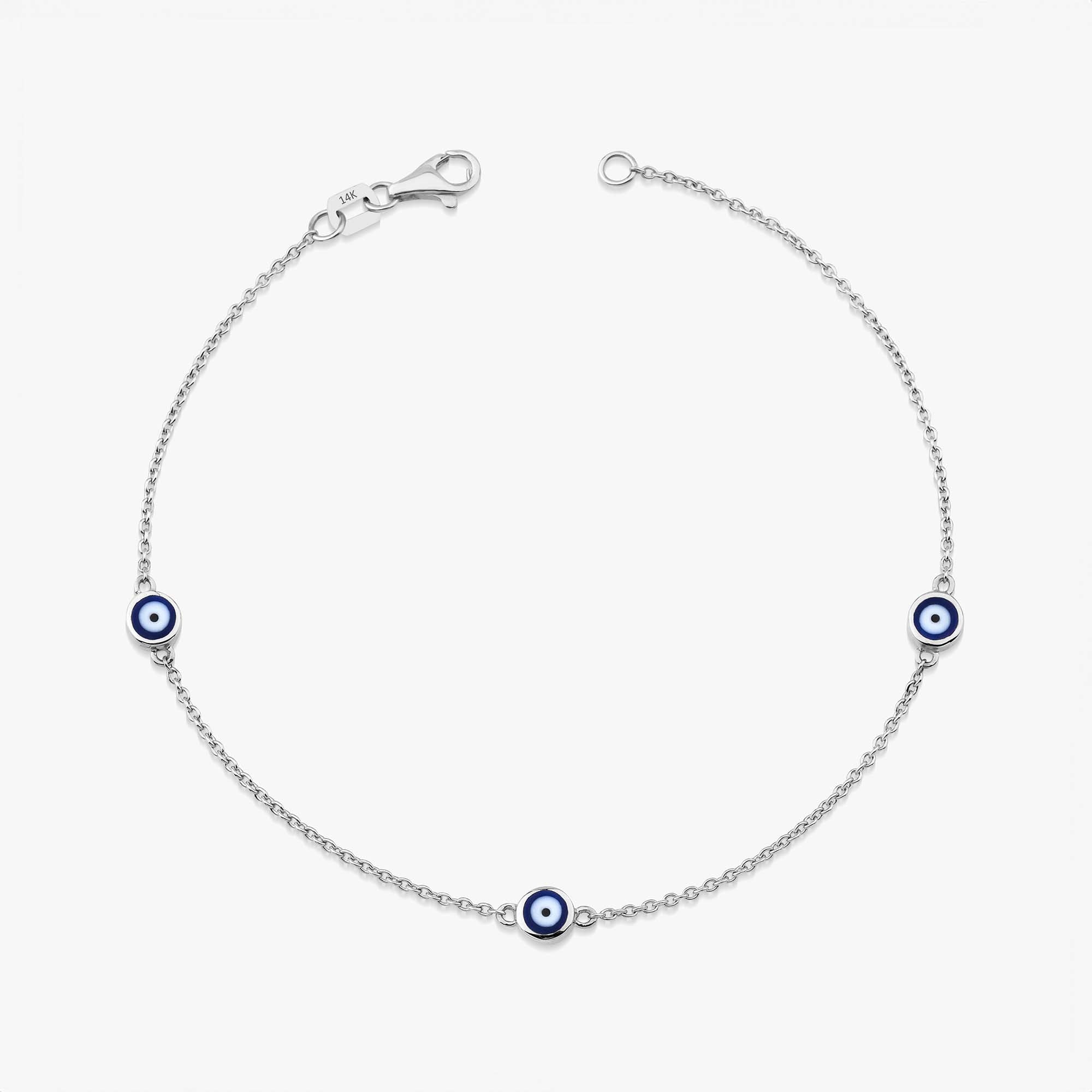 A 14 karat yellow gold bracelet with three navy blue evil eye charms on a white background