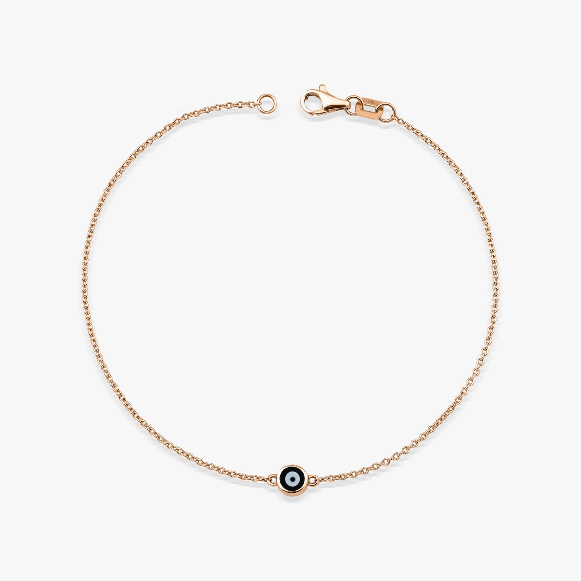 A 14K solid rose gold evil eye bracelet with a minimal black enamel design on a white background.