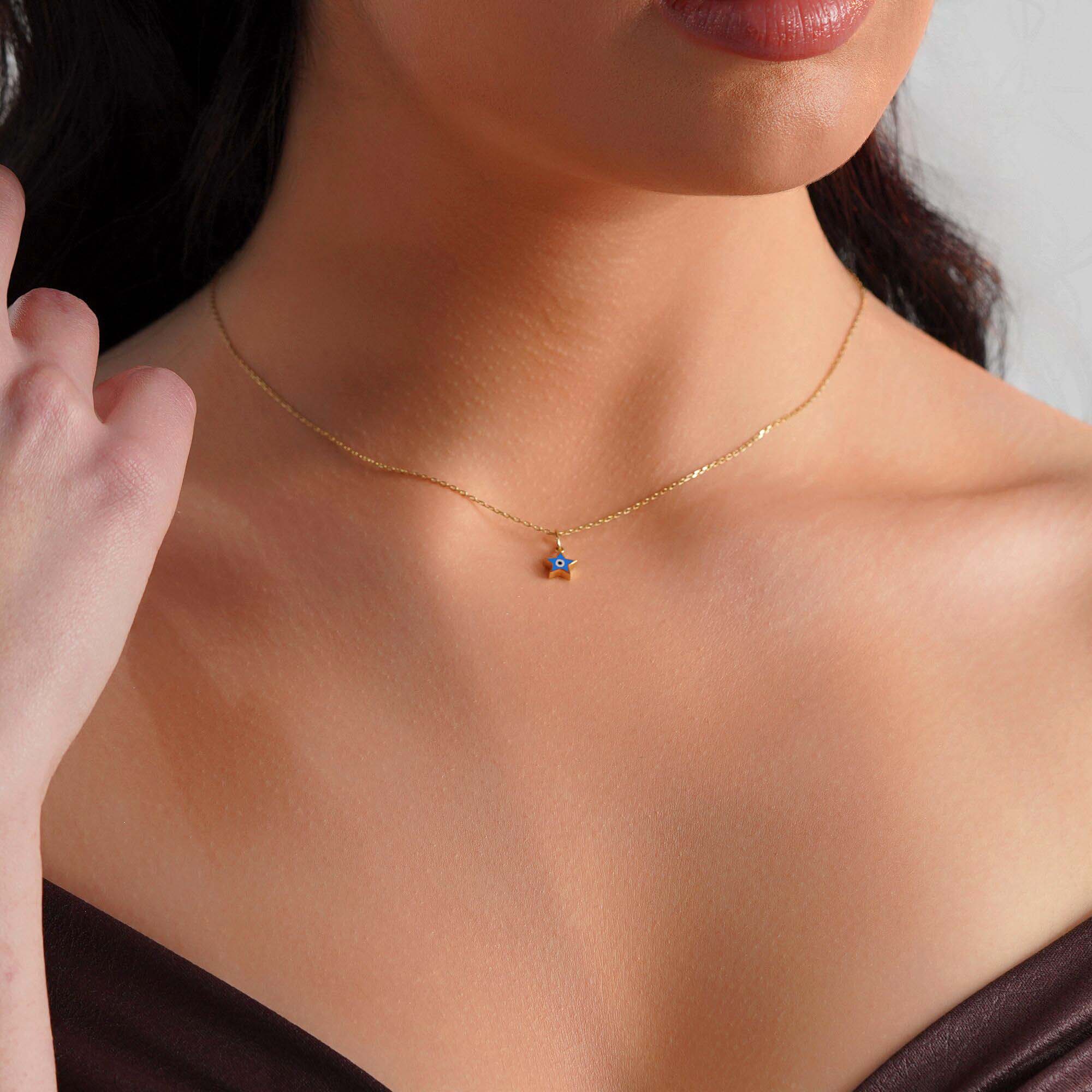 A model wearing a tiny star pendant with an evil eye center on a thin gold chain