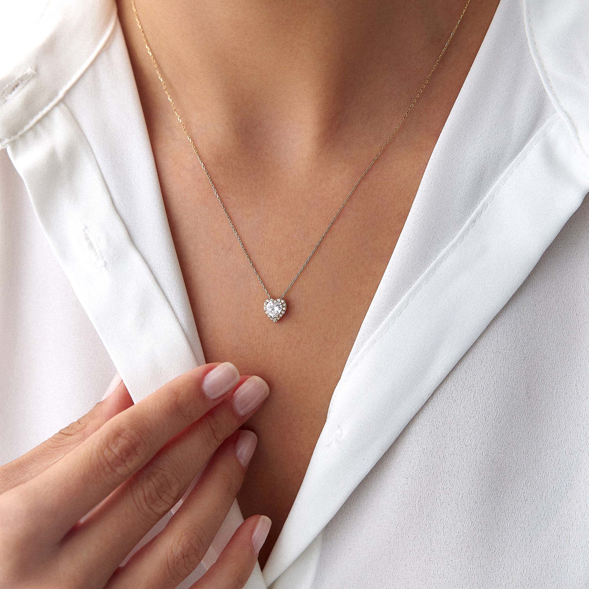 Heart-shaped cubic zirconia necklace on a person wearing a white blazer.